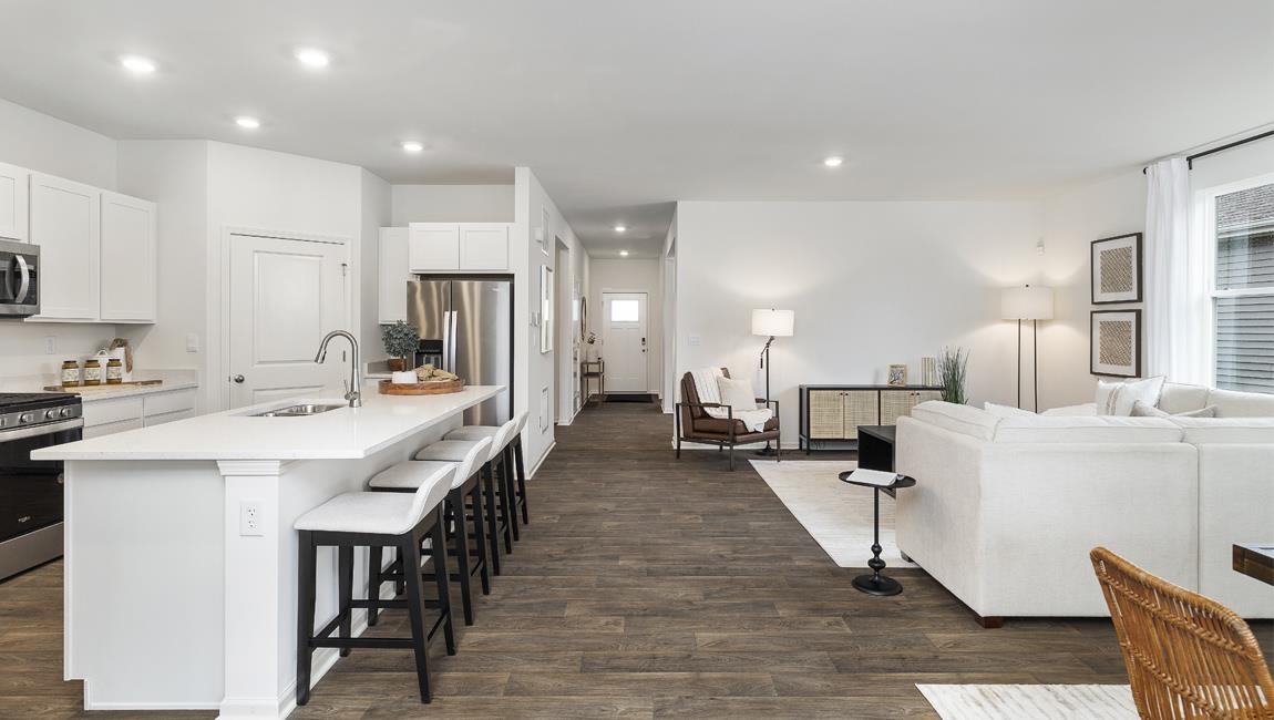 Kitchen with appliances with stainless steel finishes, sink, dark hardwood / wood-style floors, and white cabinetry