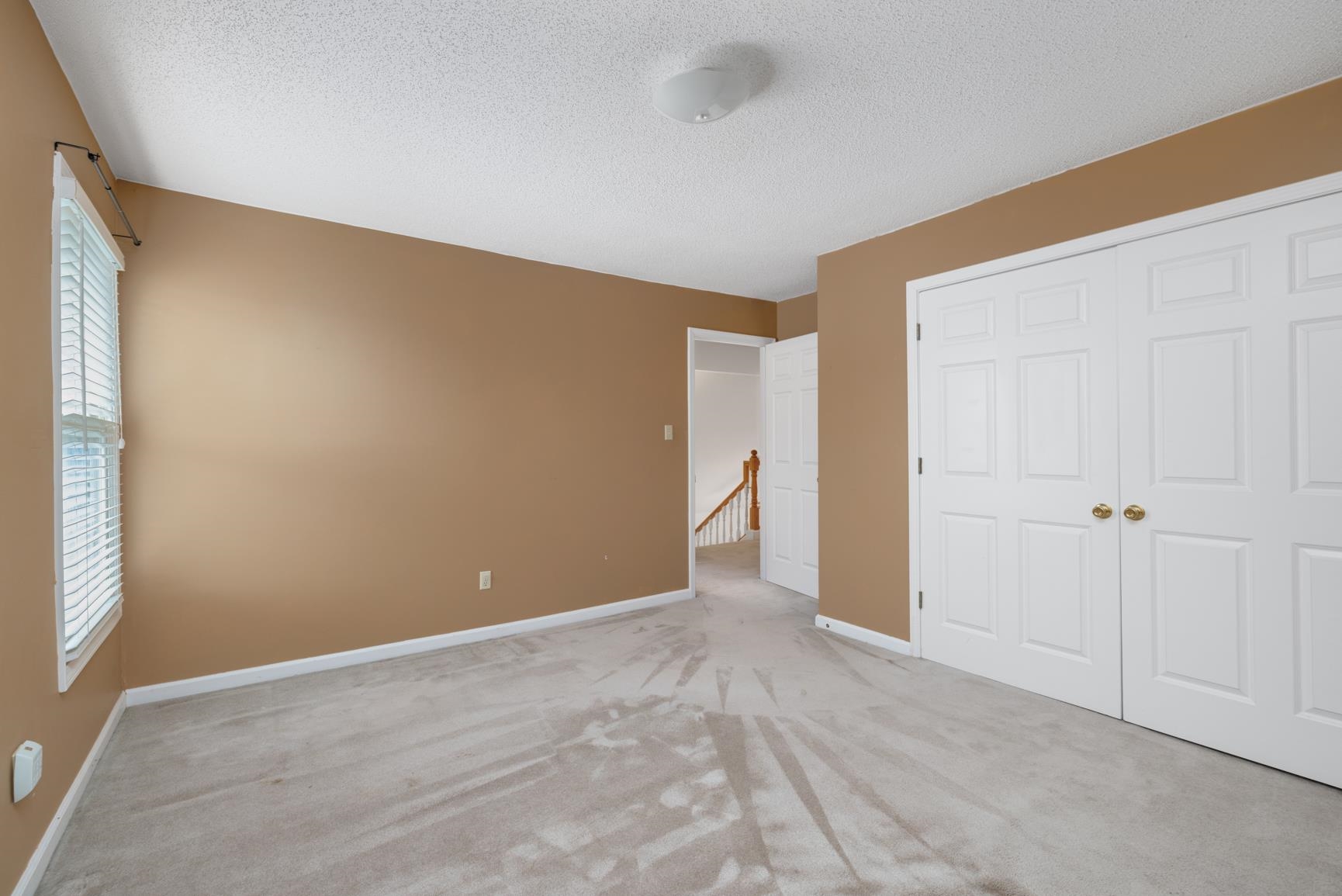 Unfurnished bedroom with light carpet, a textured ceiling, and a closet