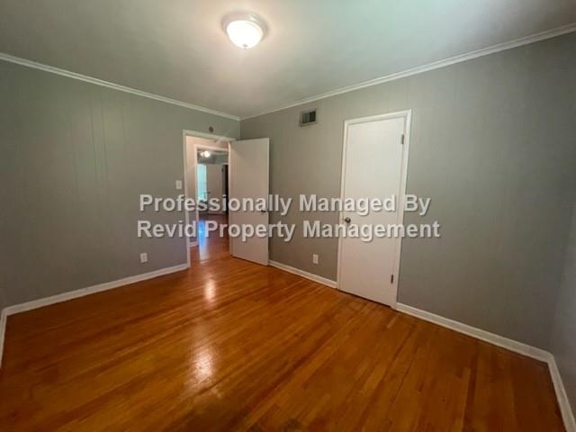 Unfurnished bedroom featuring crown molding and hardwood / wood-style floors