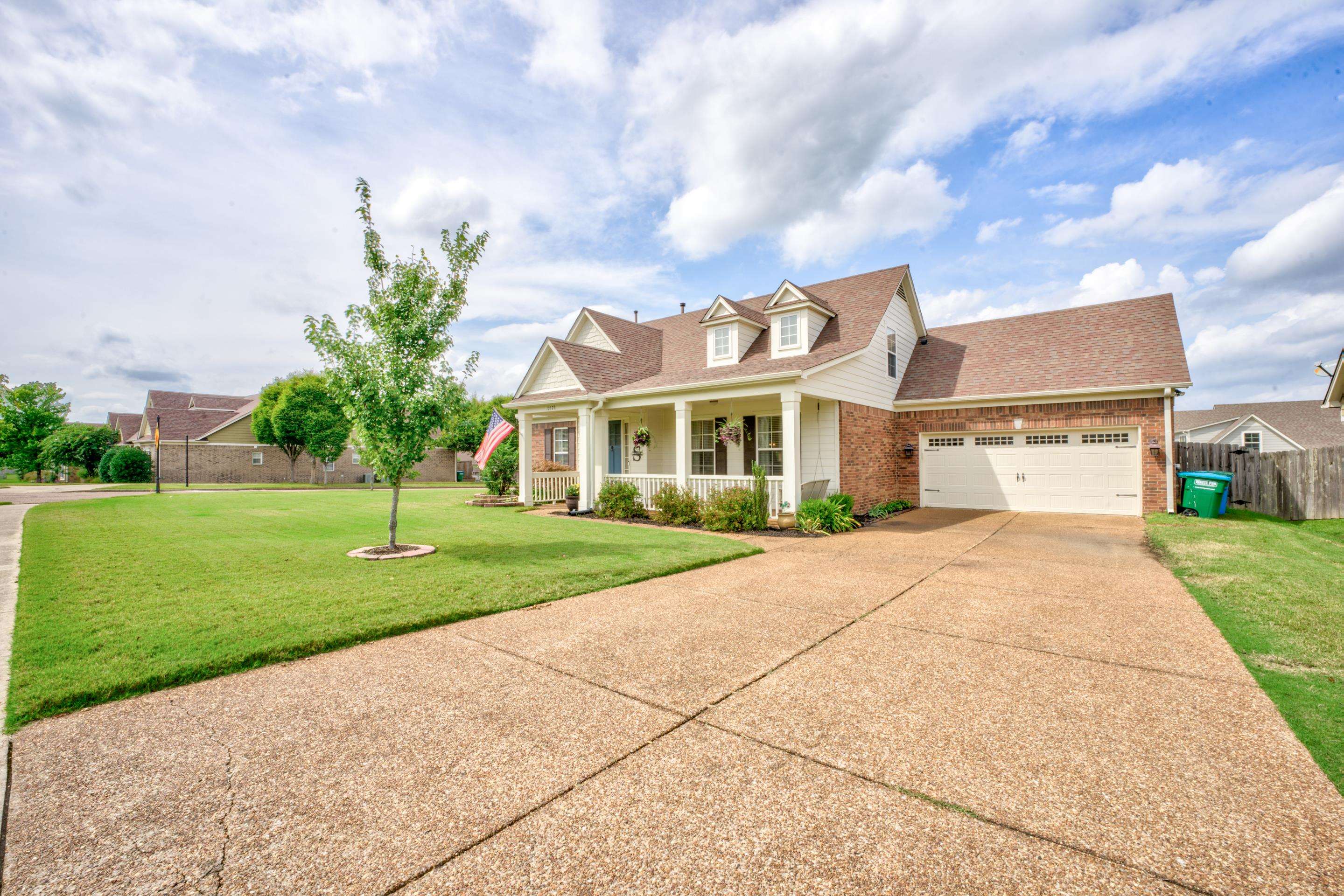 Cape cod home with a front lawn, covered porch, and a garage