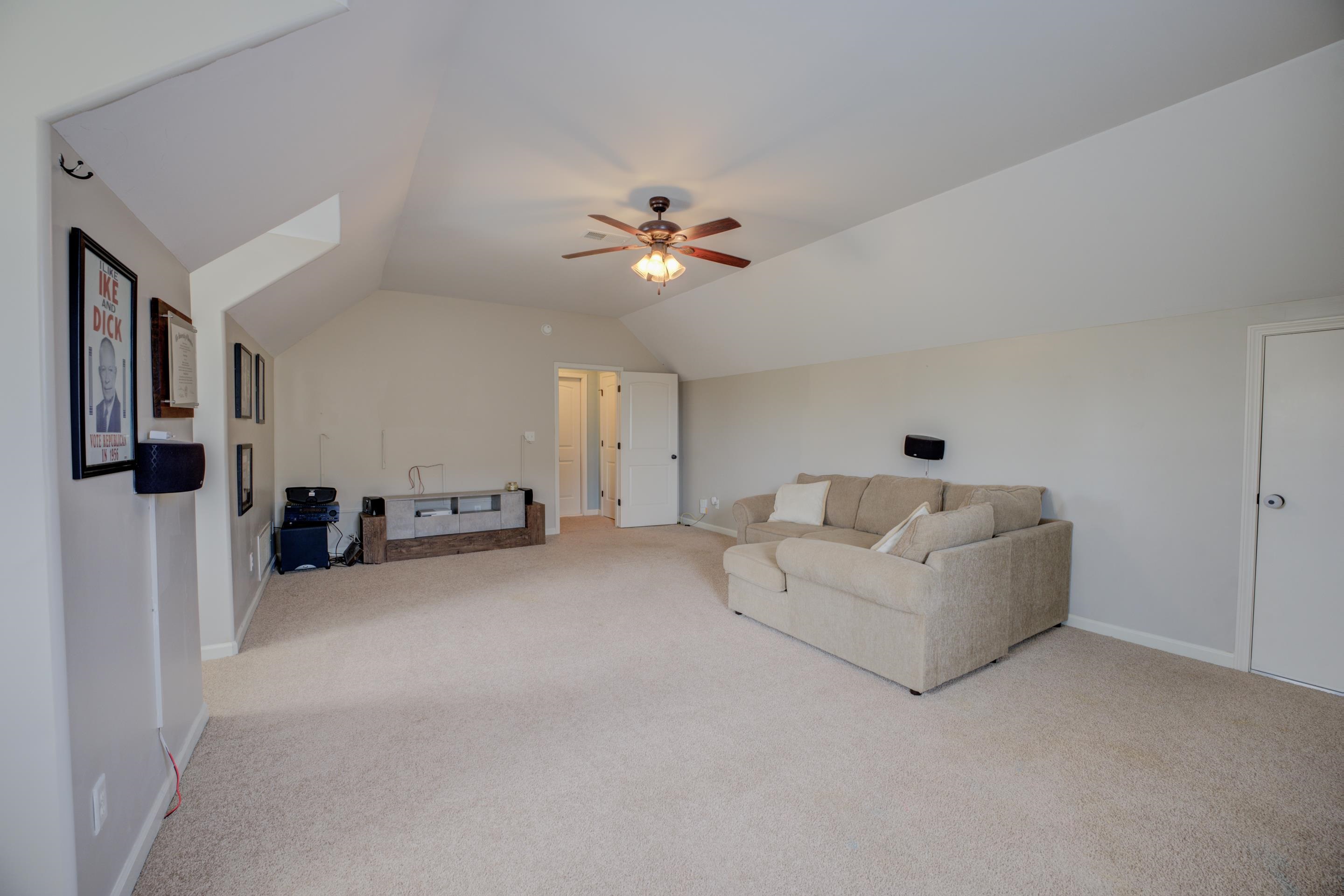 Carpeted living room with lofted ceiling and ceiling fan