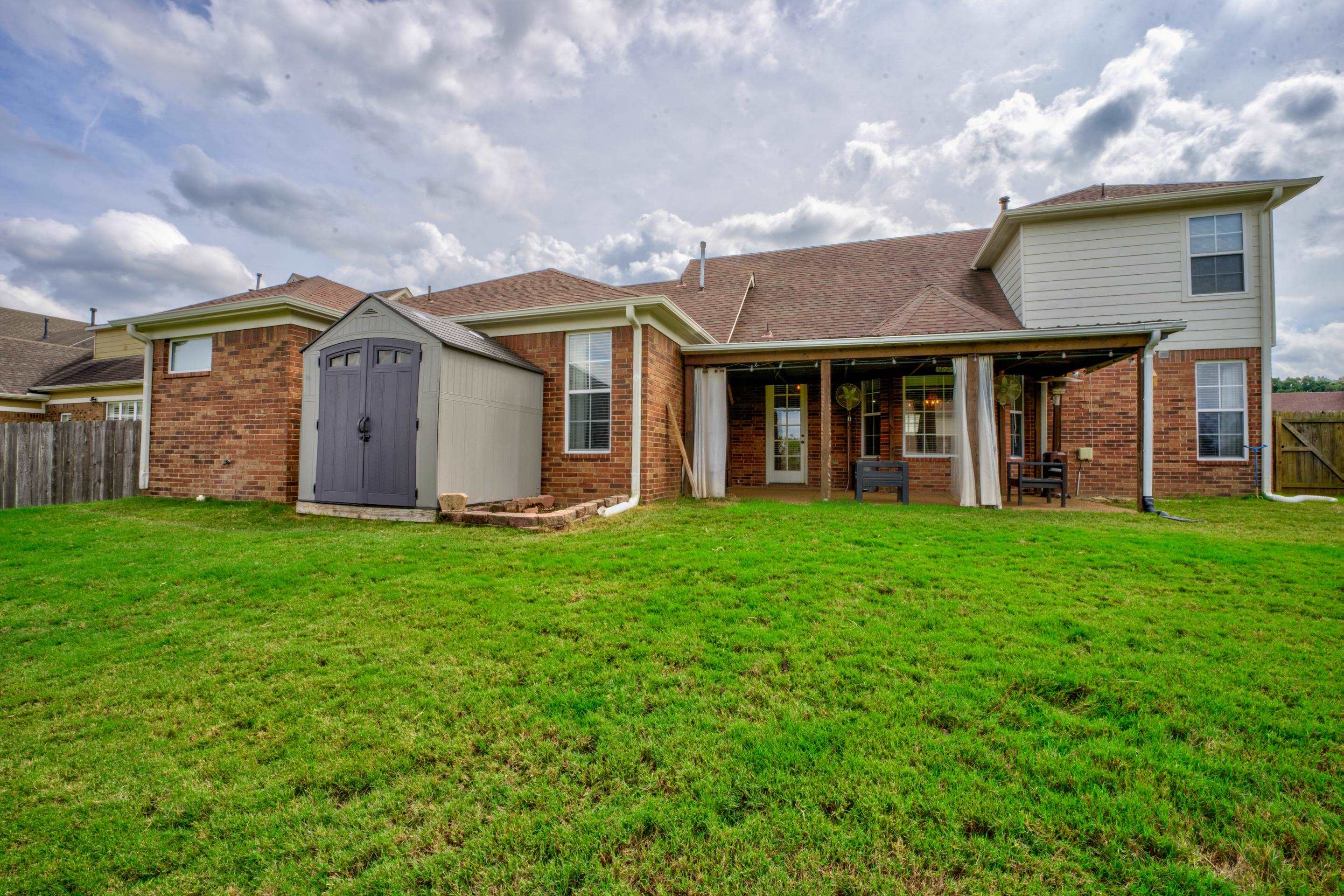 Back of house with a shed, a yard, and a patio area