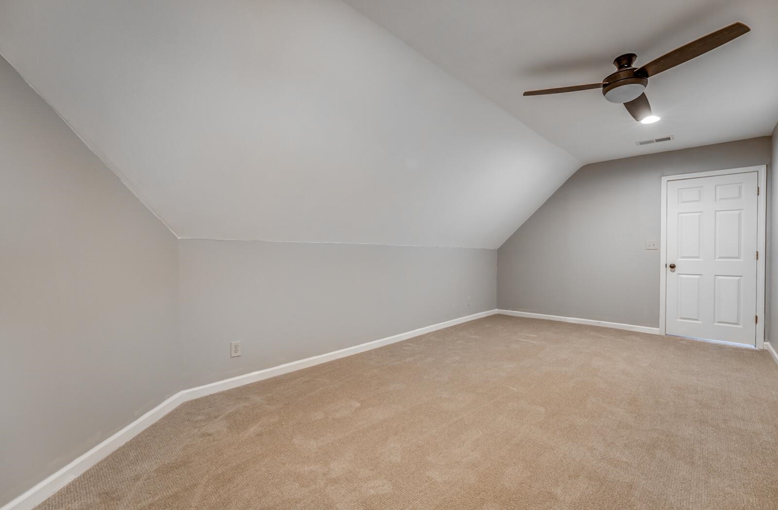 Additional living space with ceiling fan, light colored carpet, and vaulted ceiling