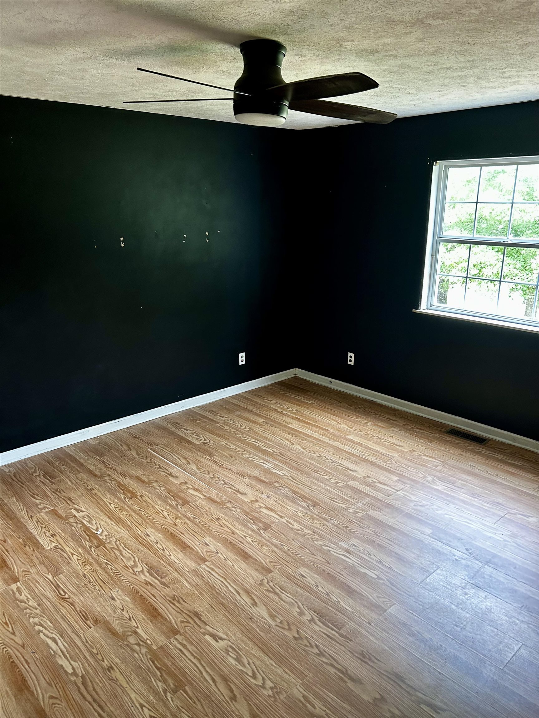 Unfurnished room with ceiling fan, a textured ceiling, and light hardwood / wood-style floors