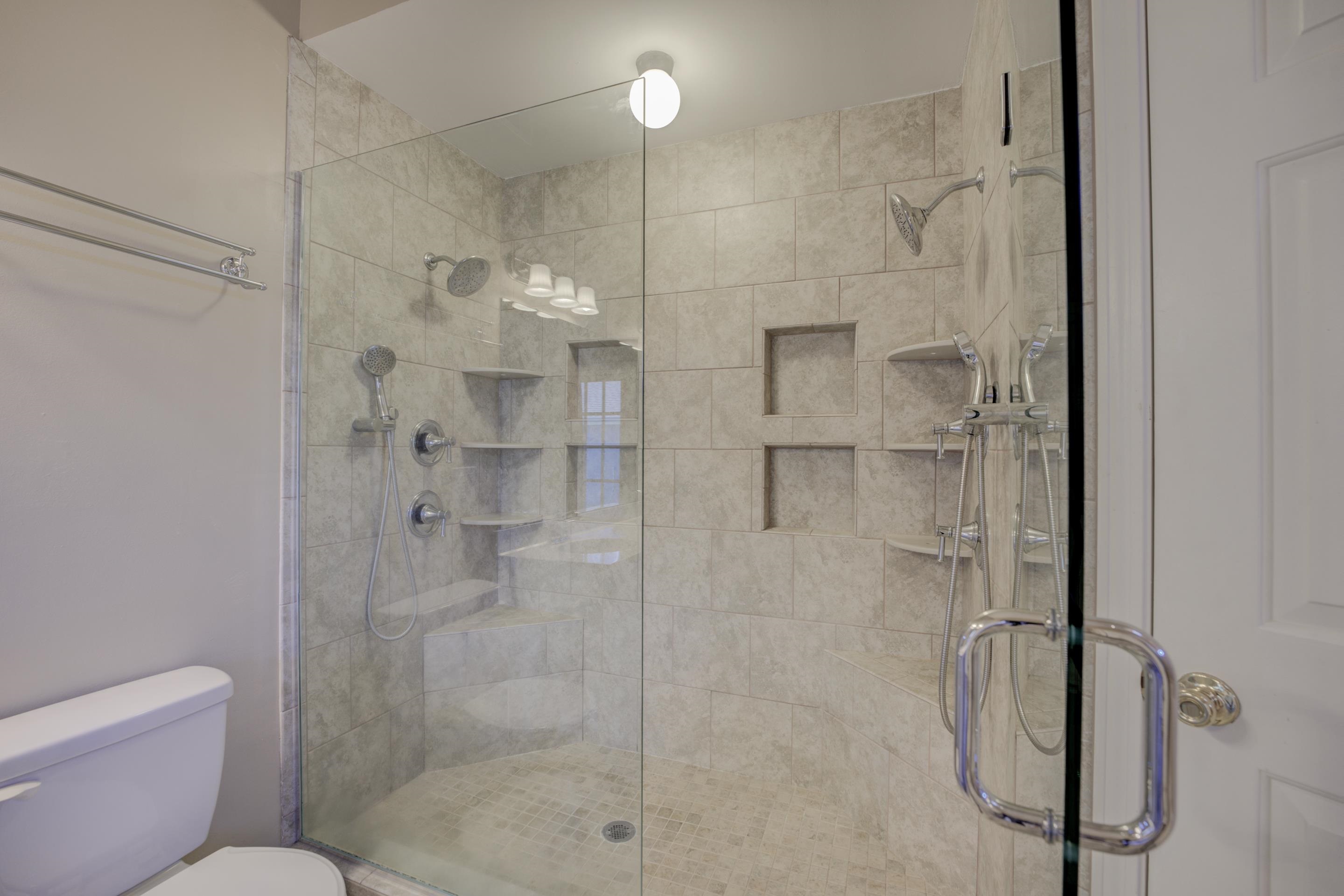 The walk-in shower has dual shower heads, and dual hand held shower heads, complete tile surround, and a frame-less shower door.