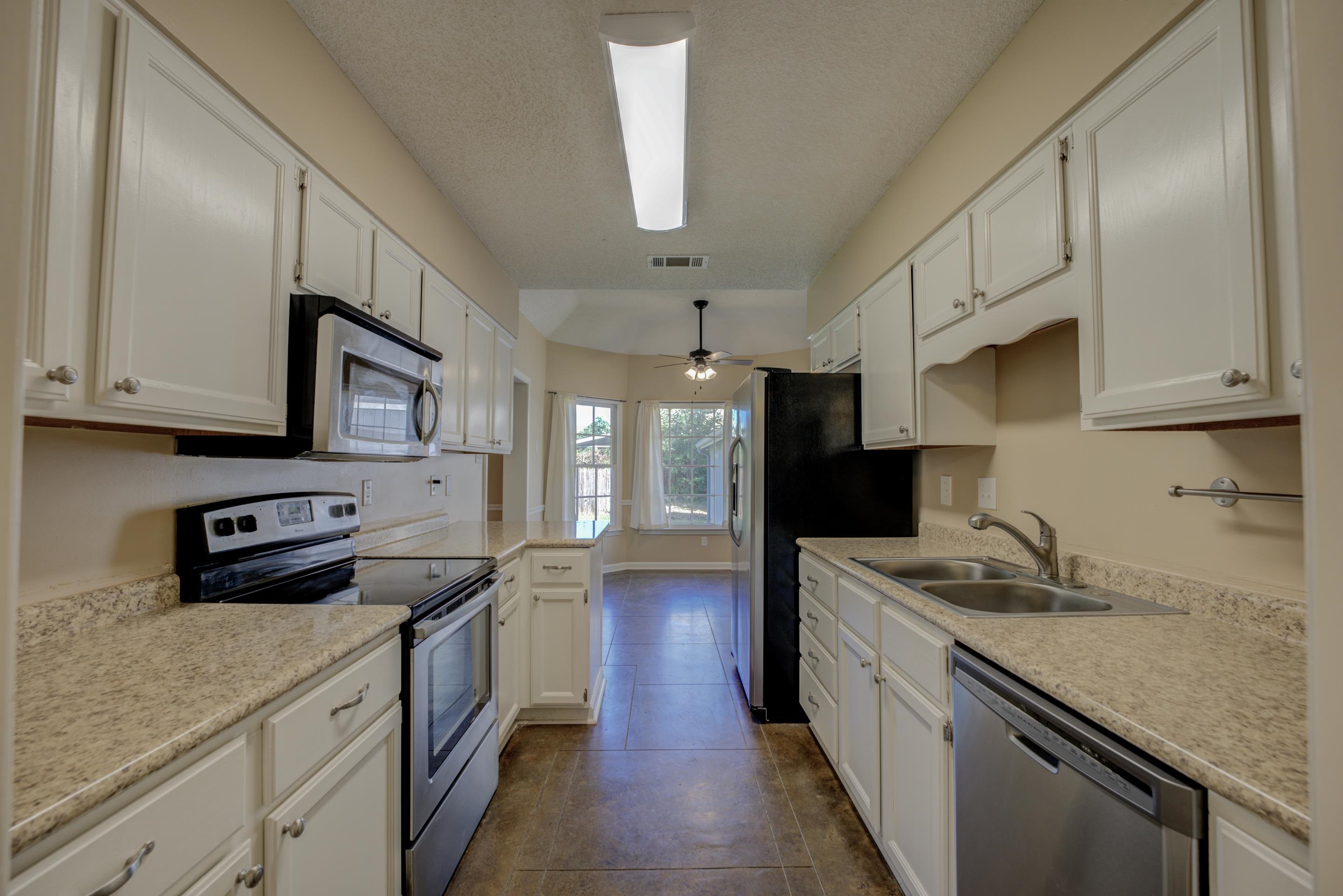 Eat-in kitchen equipped with white cabinetry, and stainless steel appliances.