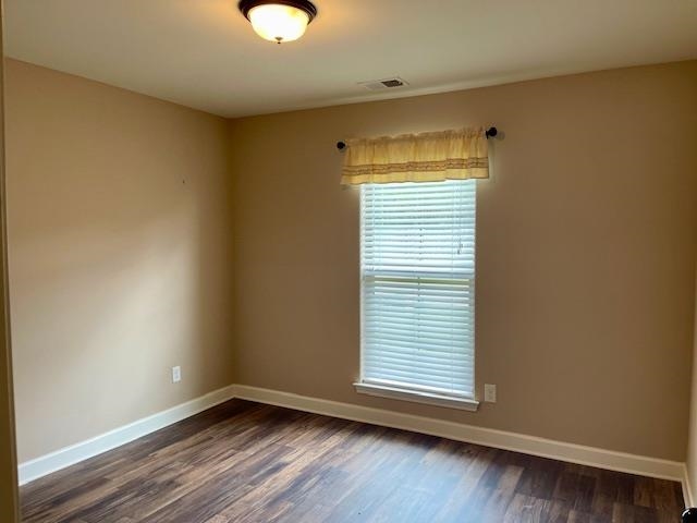 Empty room featuring dark wood-type flooring