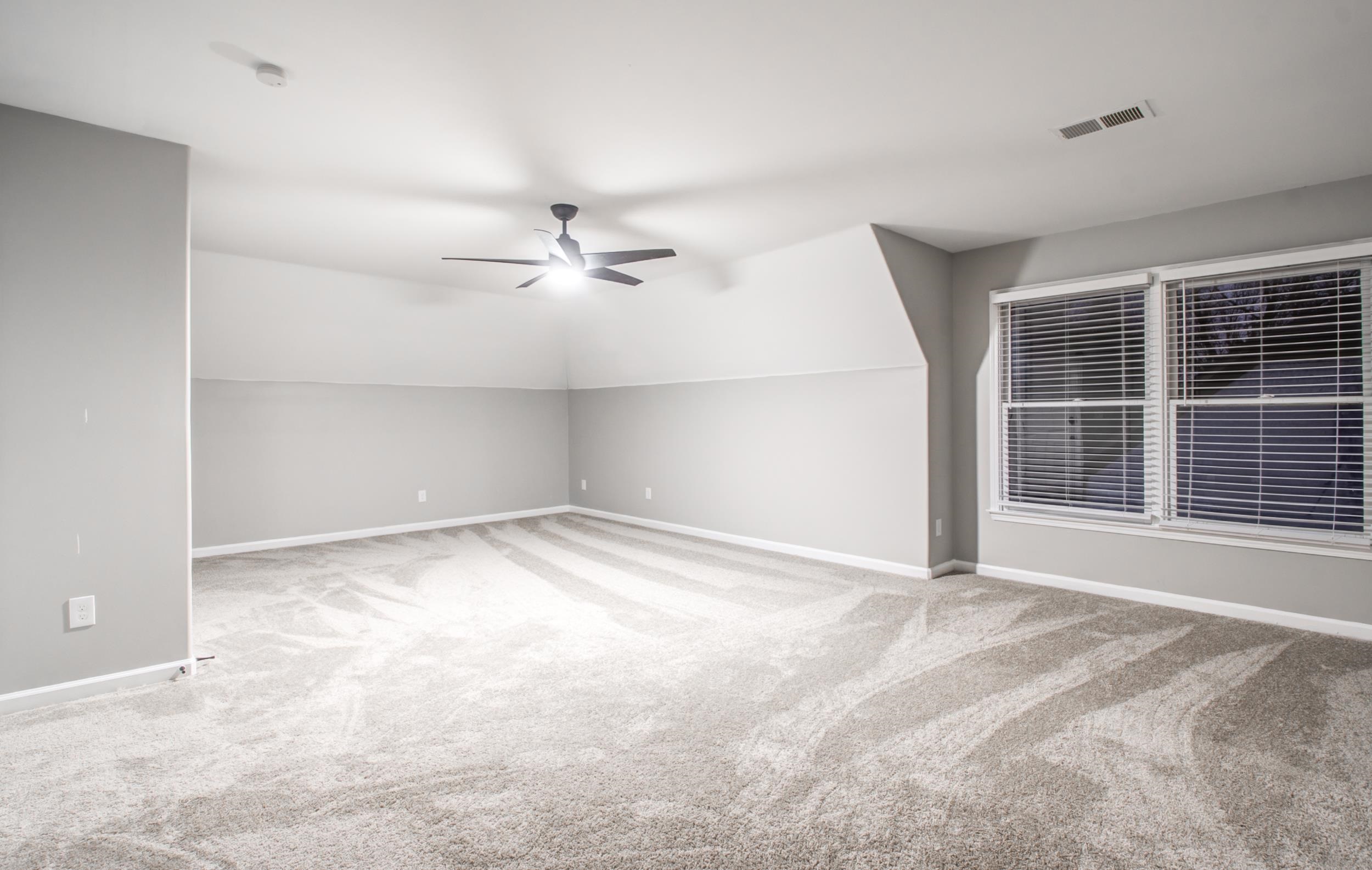 Bonus room featuring light carpet, lofted ceiling, and ceiling fan