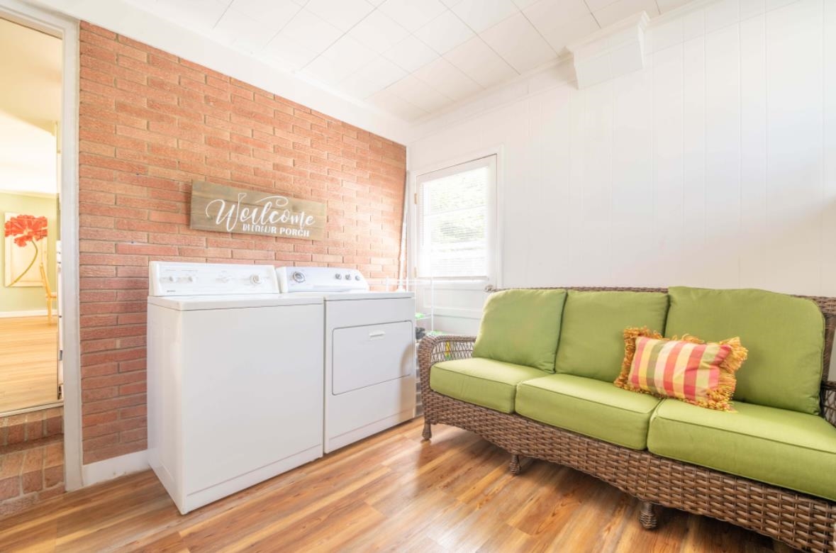 Washroom with separate washer and dryer, light hardwood / wood-style floors, and brick wall