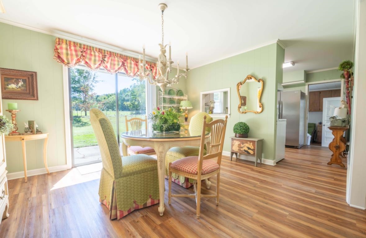 Dining area featuring wood-type flooring, crown molding, and a chandelier