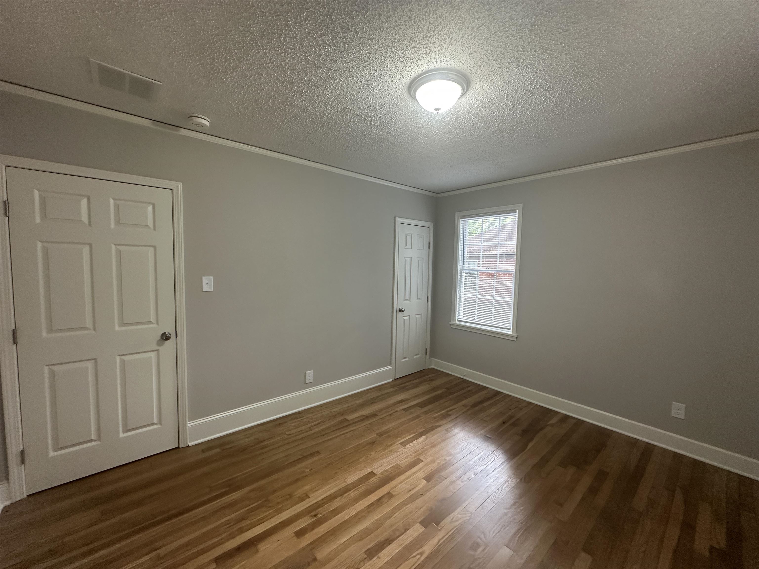 Unfurnished room with ornamental molding, a textured ceiling, and dark wood-type flooring