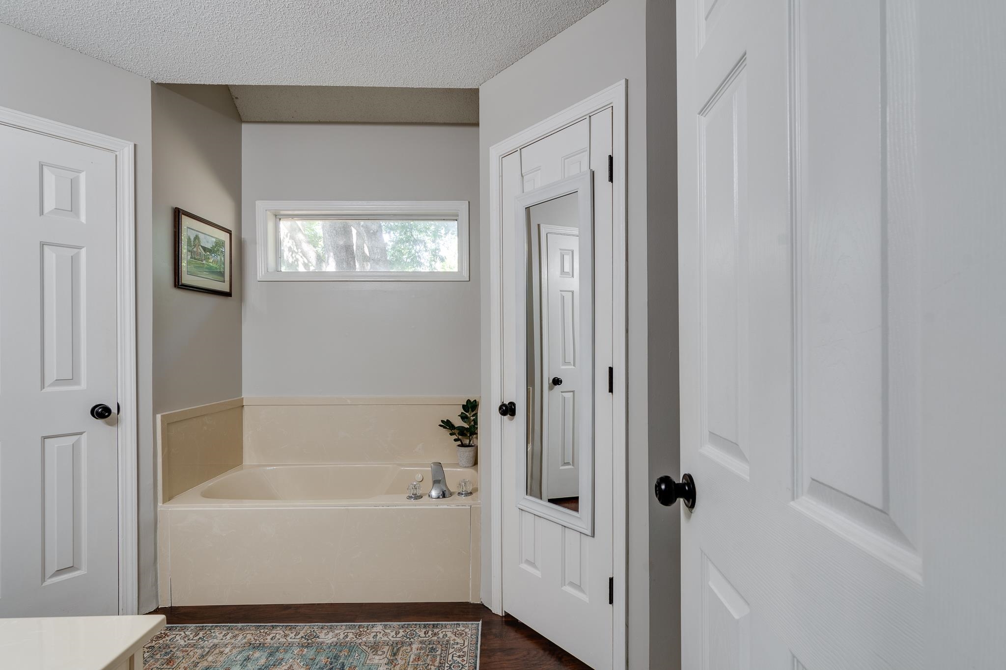 Bathroom with a textured ceiling, a bathing tub, and hardwood / wood-style flooring