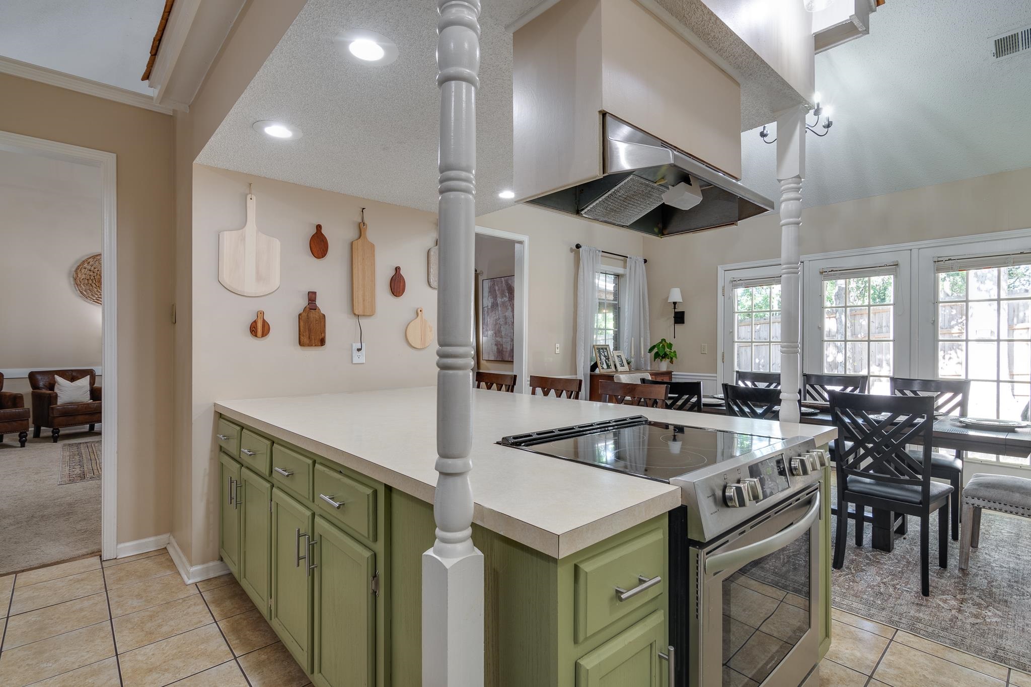 Kitchen featuring light tile patterned floors, a textured ceiling, electric range, green cabinets, and ornate columns