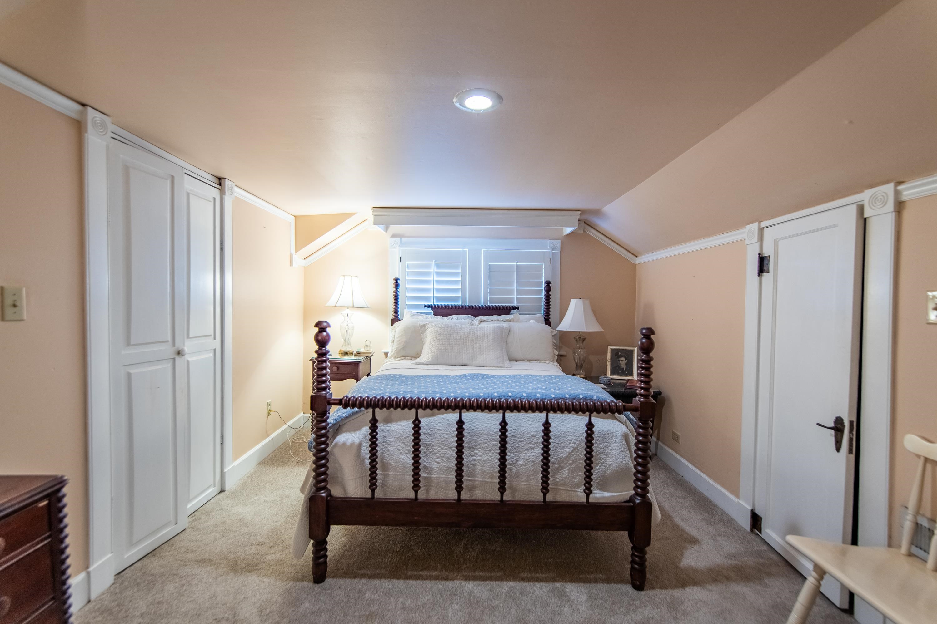 Bedroom featuring light carpet, ornamental molding, and vaulted ceiling