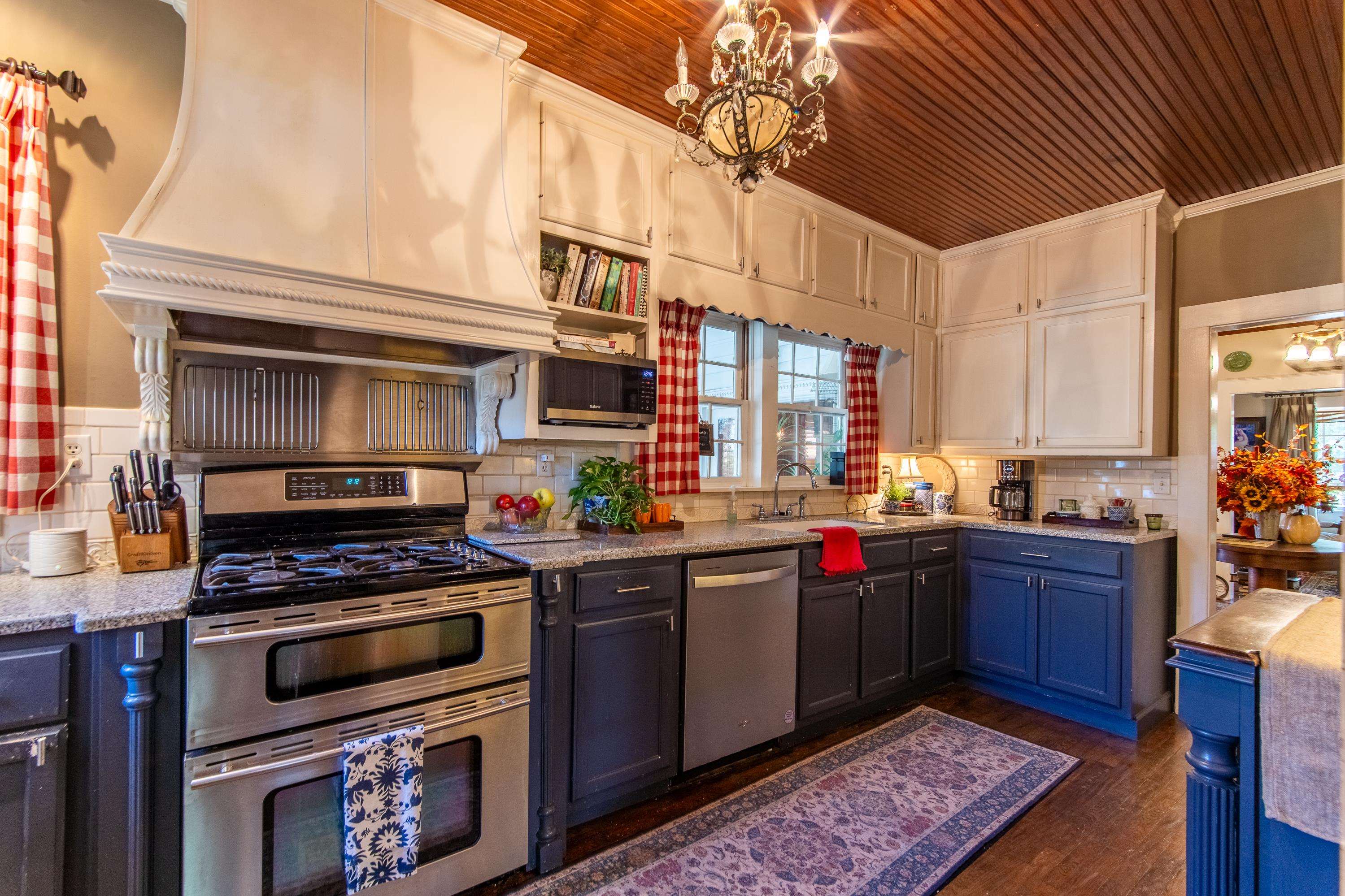 Kitchen with wood ceiling, sink, decorative backsplash, stainless steel appliances, and dark hardwood / wood-style flooring