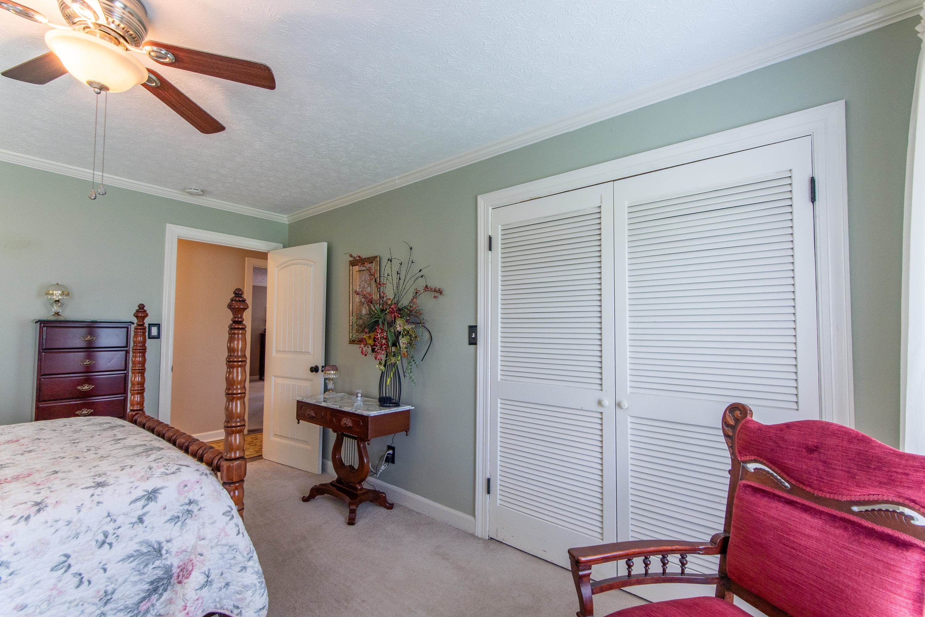 Carpeted bedroom featuring ceiling fan, a textured ceiling, a closet, and crown molding