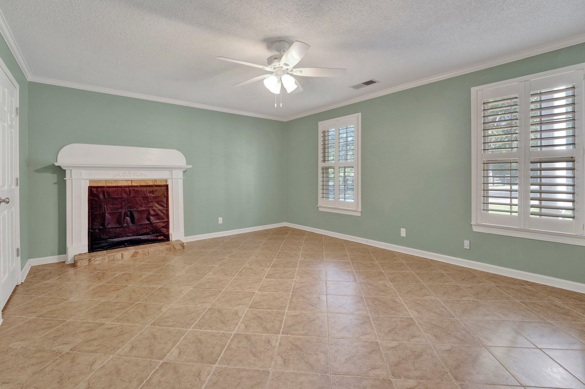 Unfurnished living room with ceiling fan, a textured ceiling, crown molding, and a healthy amount of sunlight