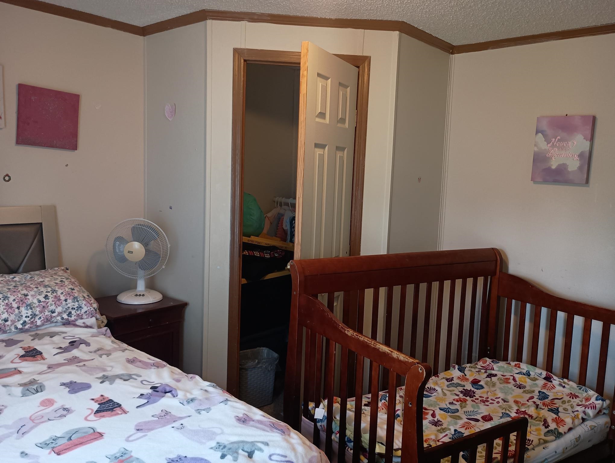 Bedroom featuring a textured ceiling, crown molding, a nursery area, and a closet