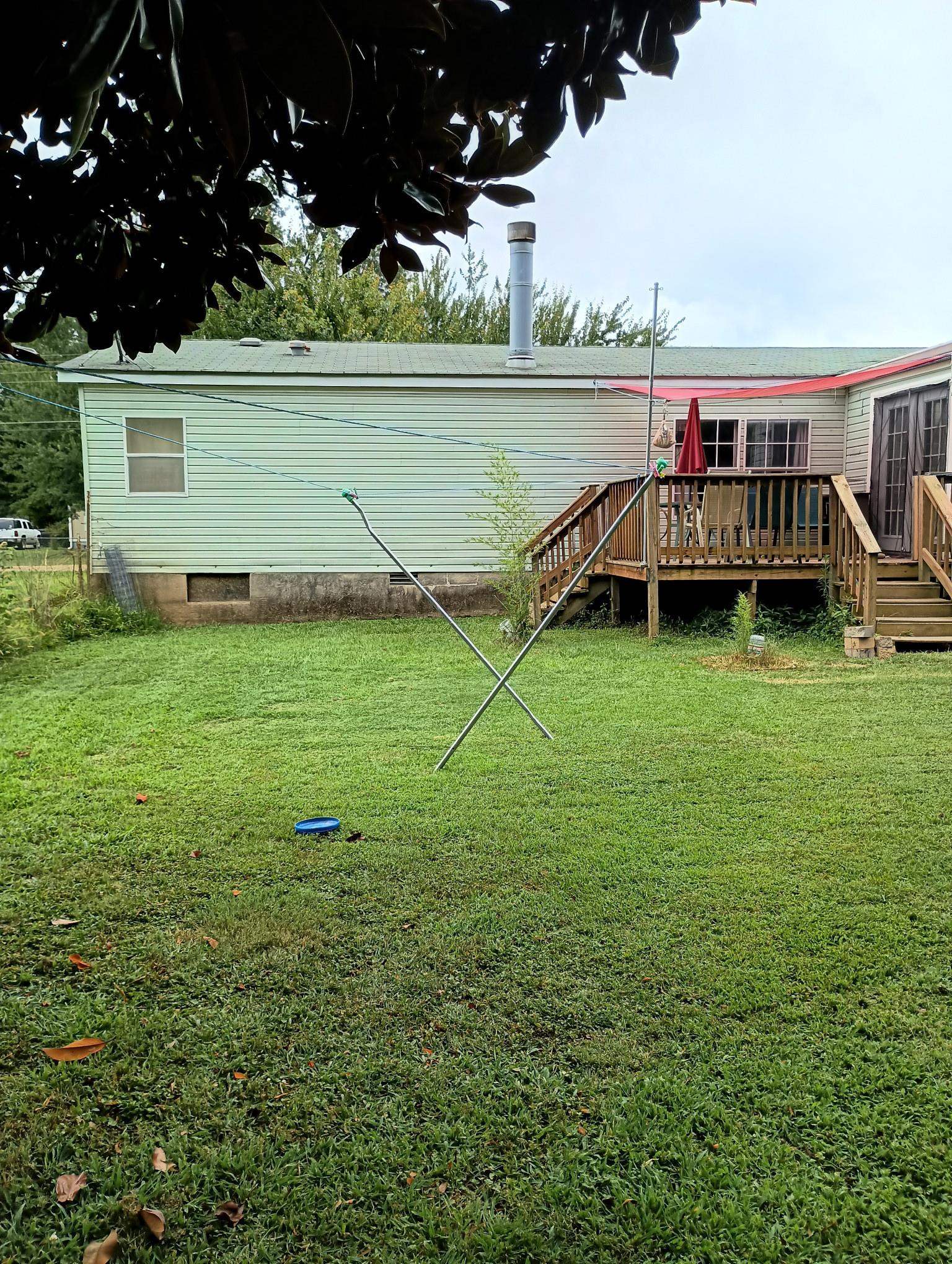 Back of property featuring a lawn and a deck