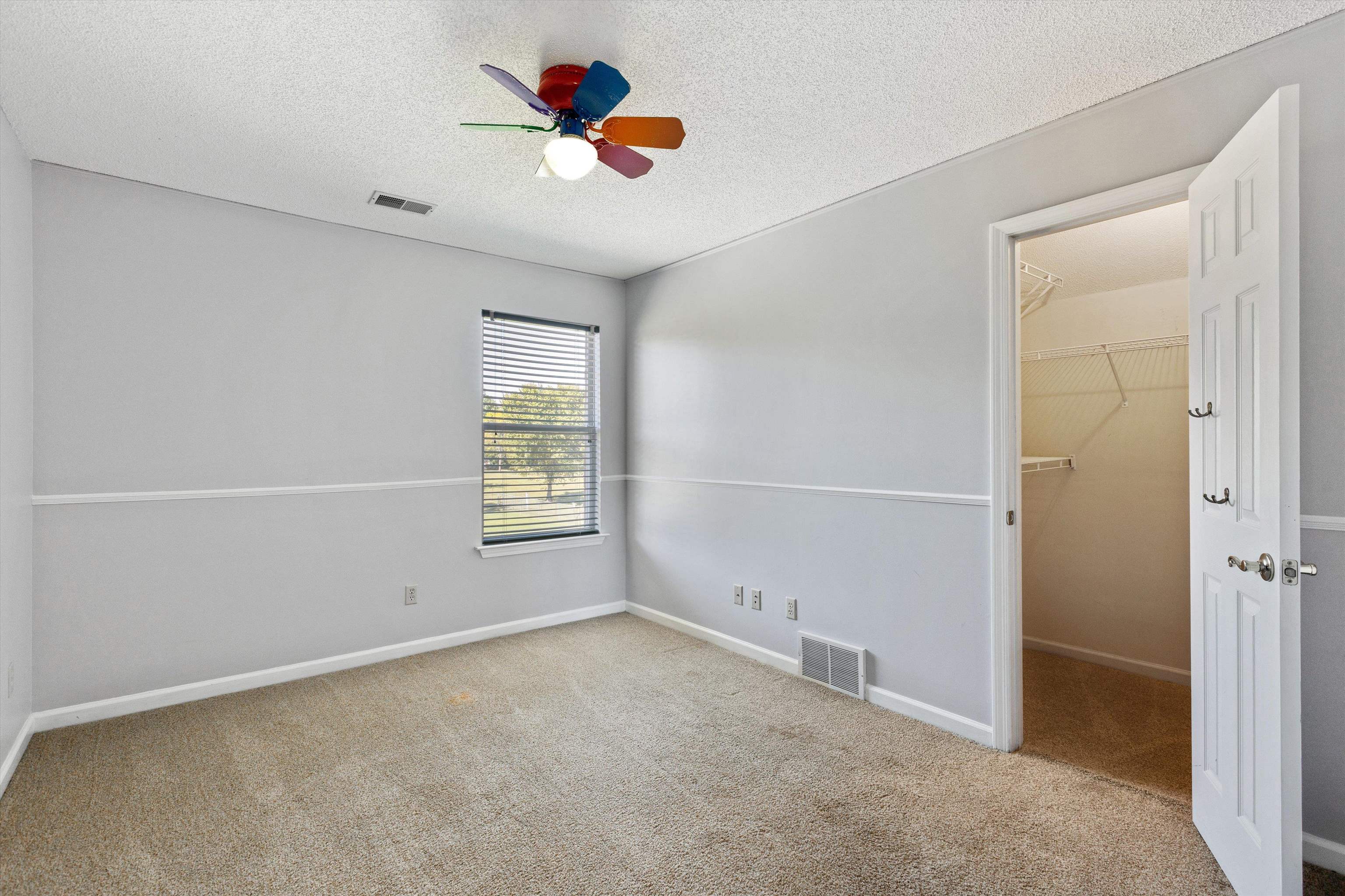 Carpeted spare room featuring a textured ceiling and ceiling fan