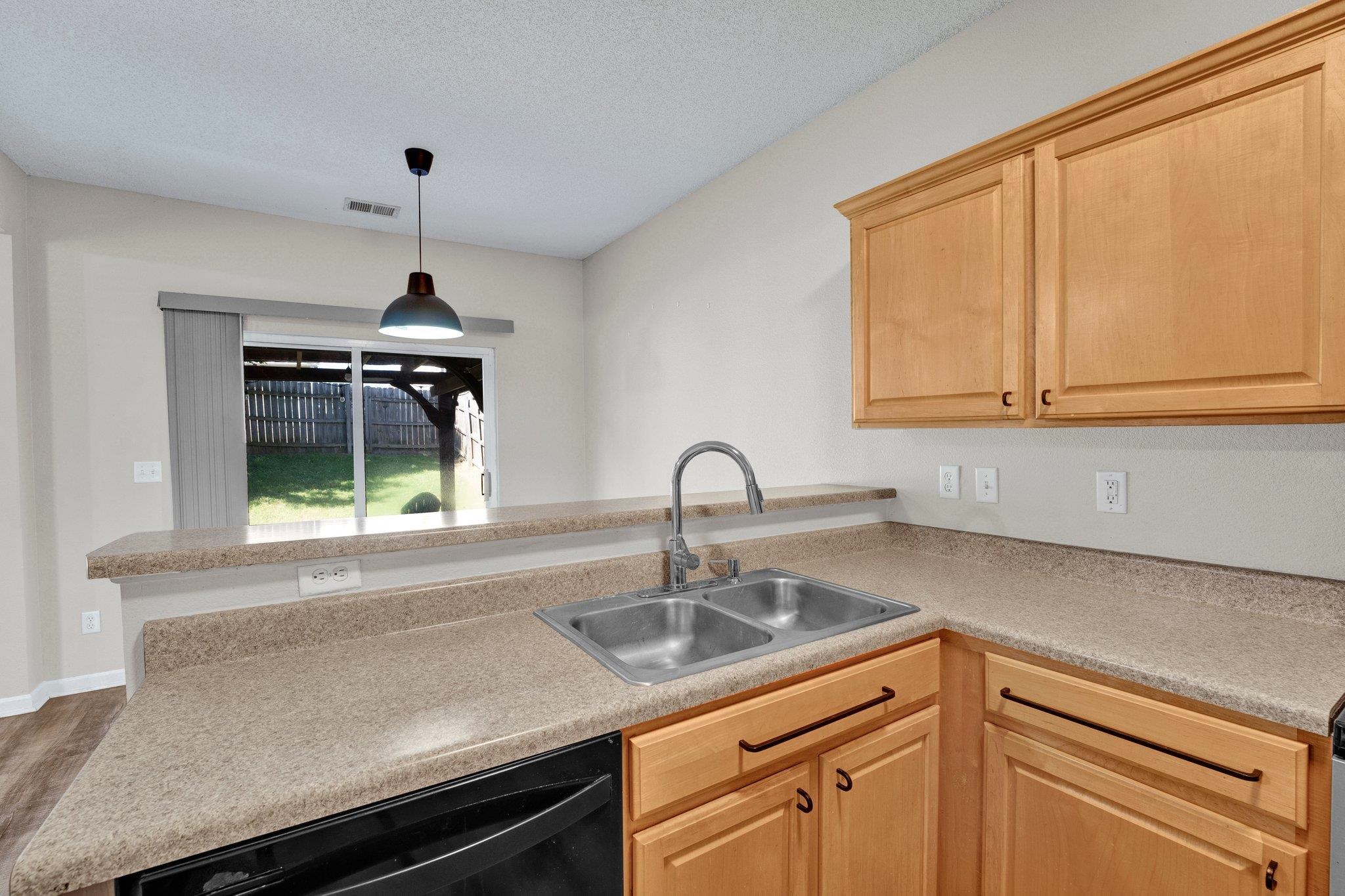 Kitchen with pendant lighting, dishwasher, sink, light brown cabinets, and dark hardwood / wood-style flooring