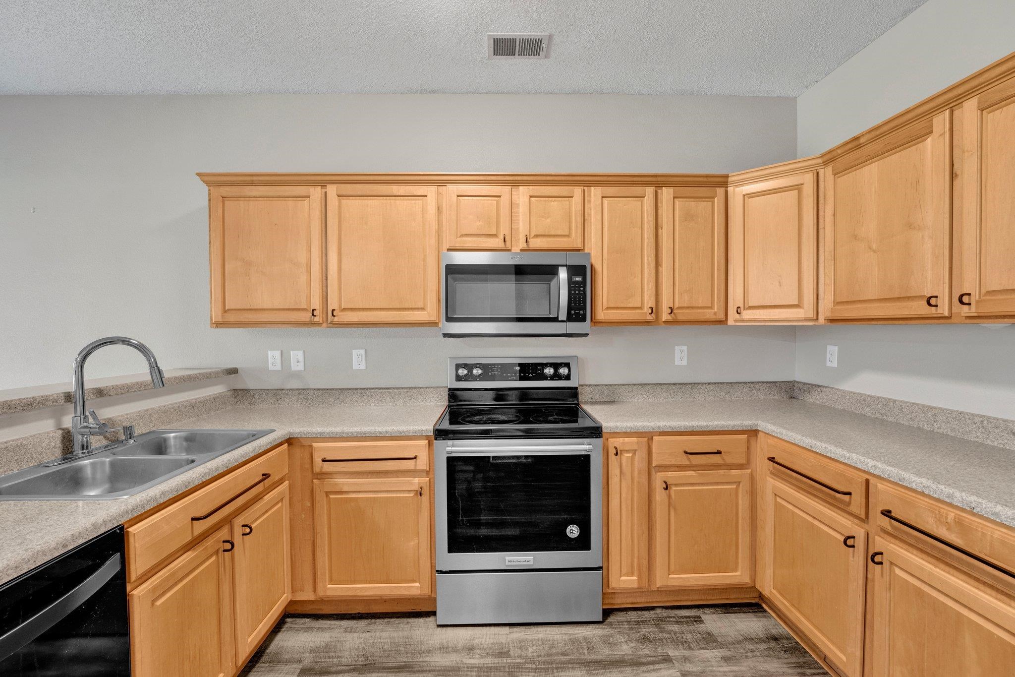 Kitchen with a textured ceiling, light brown cabinetry, sink, and stainless steel appliances