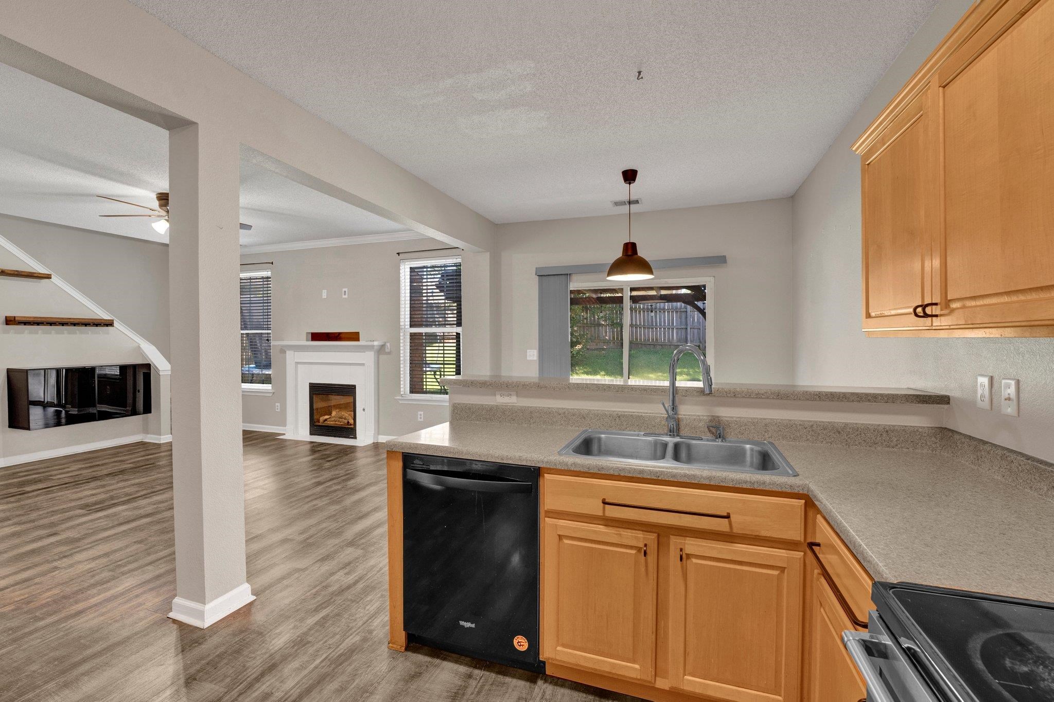 Kitchen with black dishwasher, a textured ceiling, sink, hardwood / wood-style floors, and light brown cabinetry