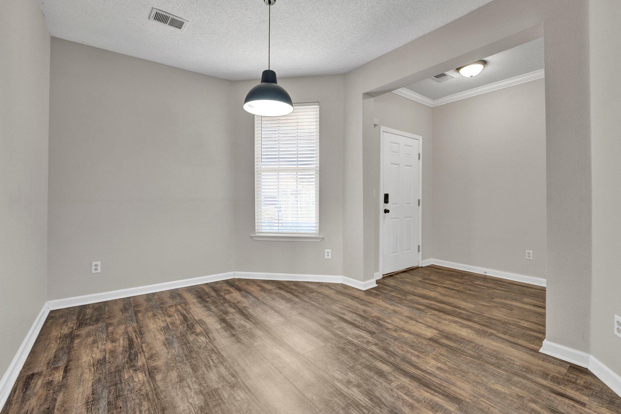 Interior space with a textured ceiling, crown molding, and dark hardwood / wood-style floors