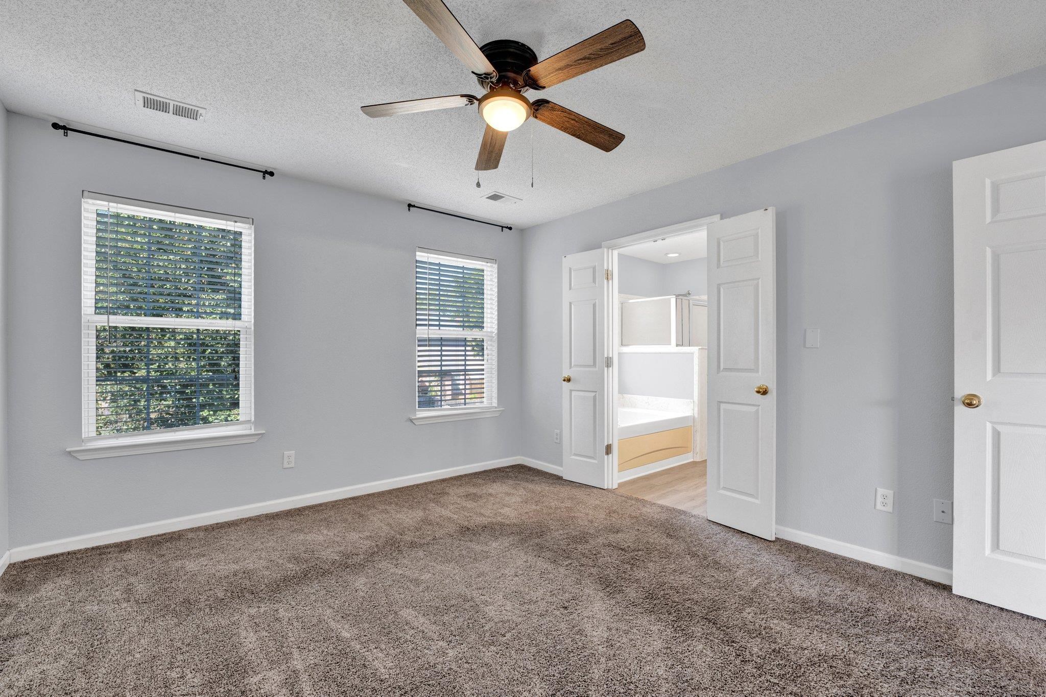Unfurnished bedroom with ensuite bath, a textured ceiling, carpet floors, and ceiling fan