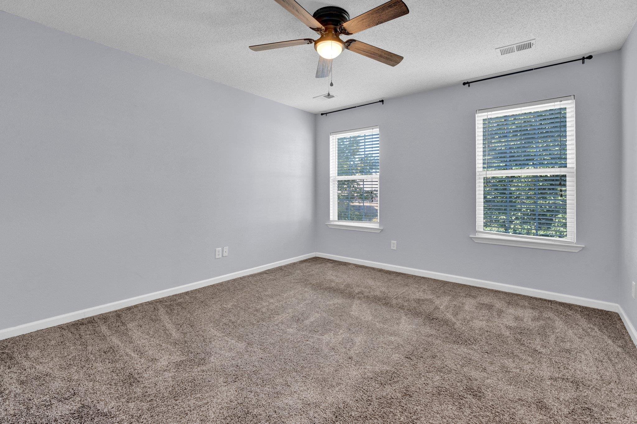 Unfurnished room with ceiling fan, a textured ceiling, plenty of natural light, and carpet