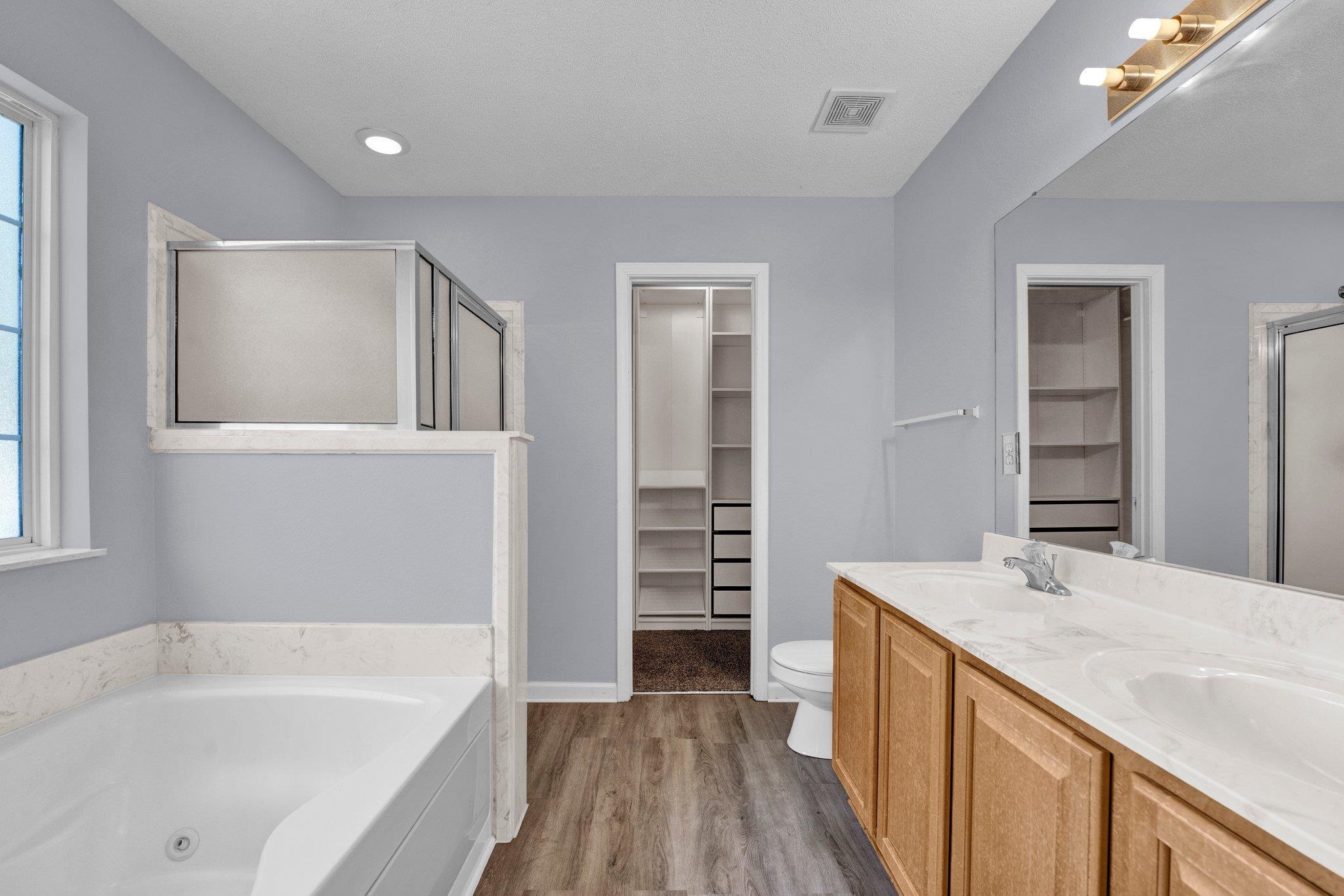 Full bathroom featuring independent shower and bath, hardwood / wood-style flooring, a healthy amount of sunlight, and toilet