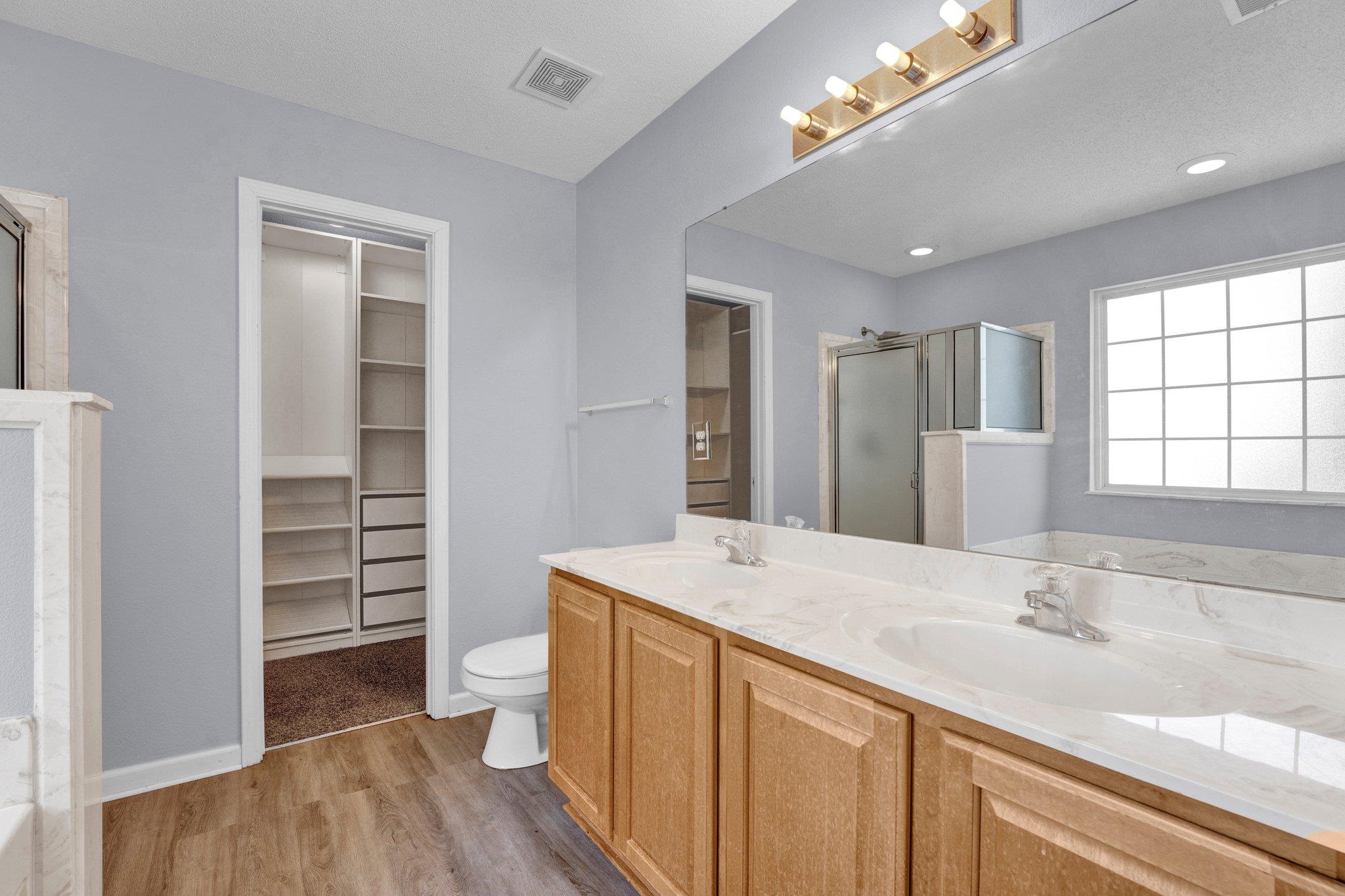 Bathroom featuring vanity, wood-type flooring, a textured ceiling, toilet, and a shower with door