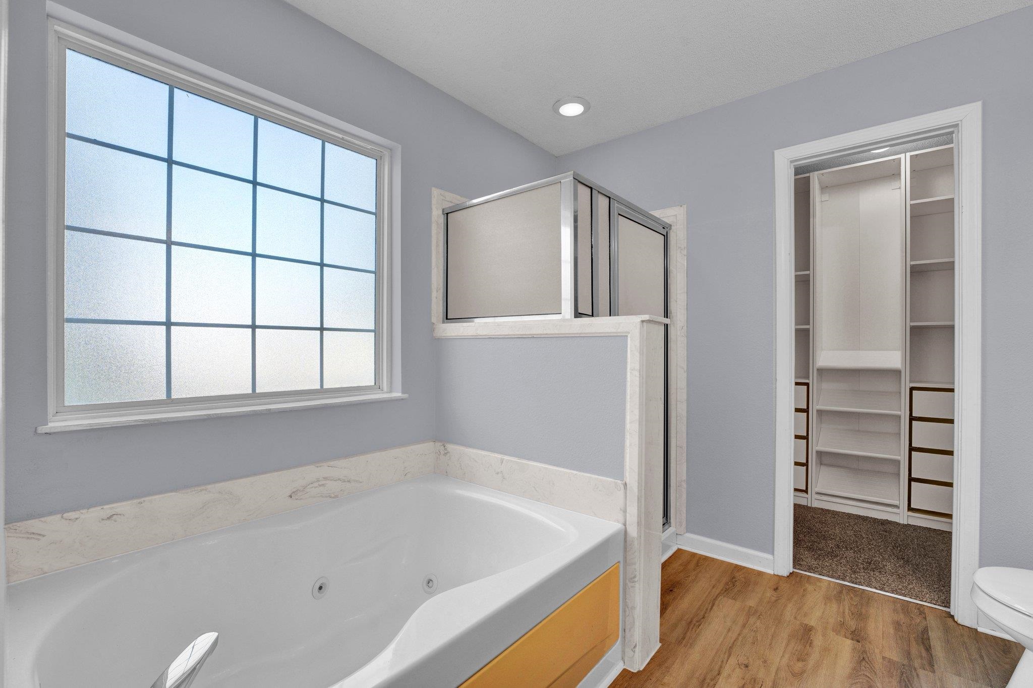 Bathroom with plus walk in shower, hardwood / wood-style flooring, and toilet