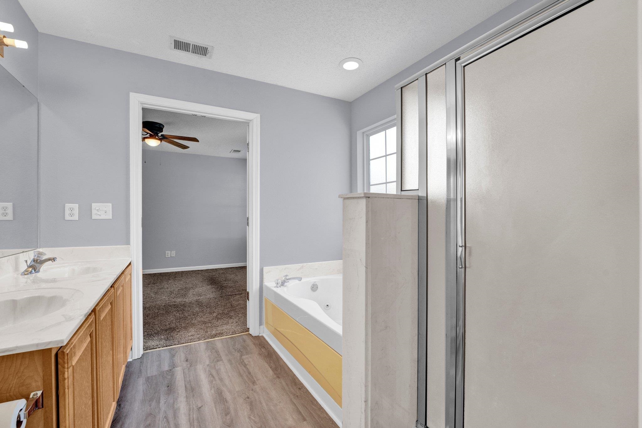 Bathroom featuring vanity, a textured ceiling, independent shower and bath, wood-type flooring, and ceiling fan