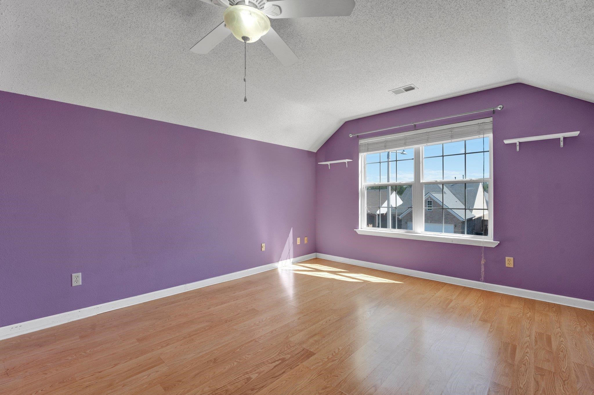 Bonus room with light wood-type flooring, vaulted ceiling, a textured ceiling, and ceiling fan