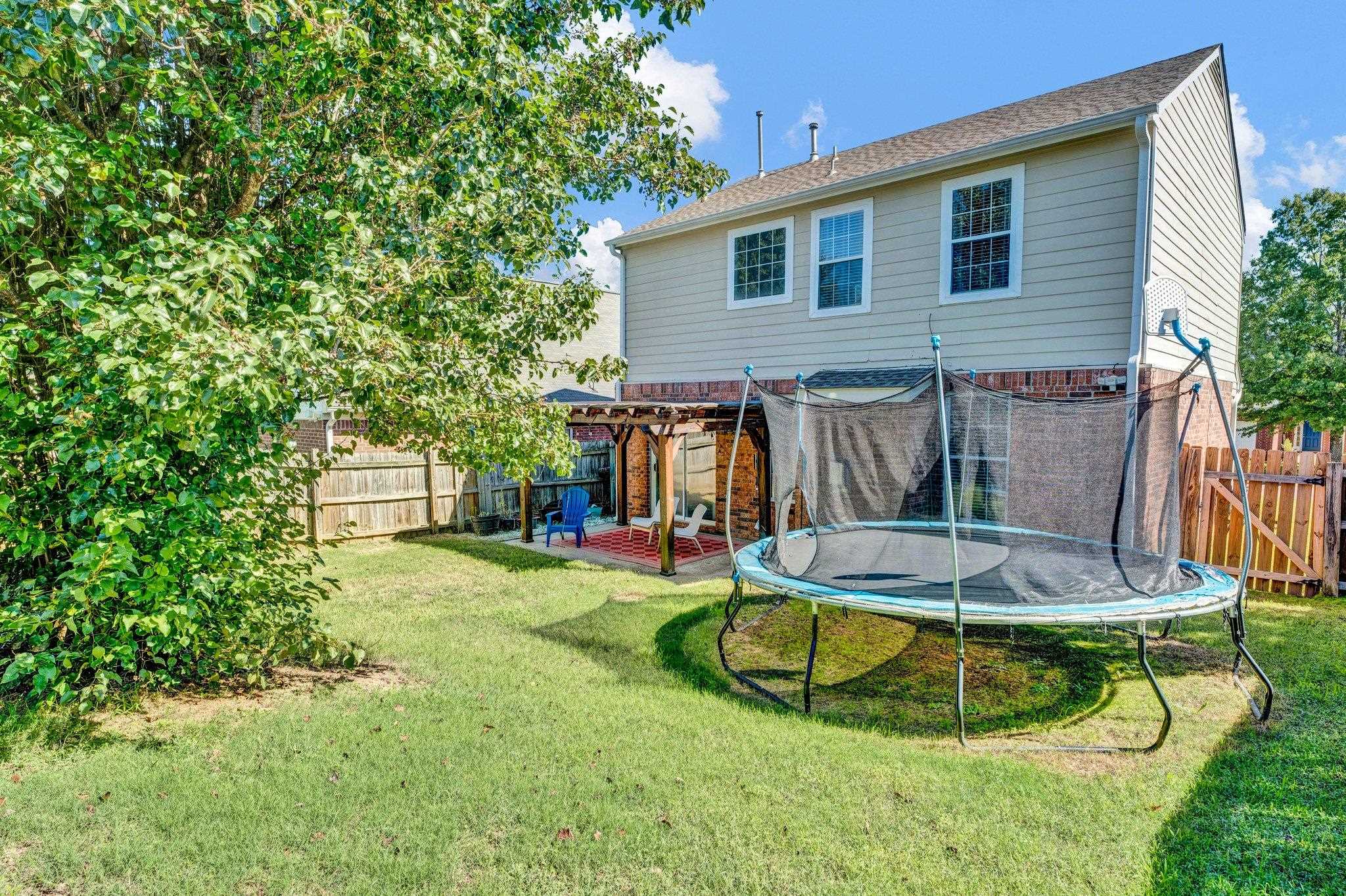 Back of house featuring a lawn, a pergola, a trampoline, and a patio area