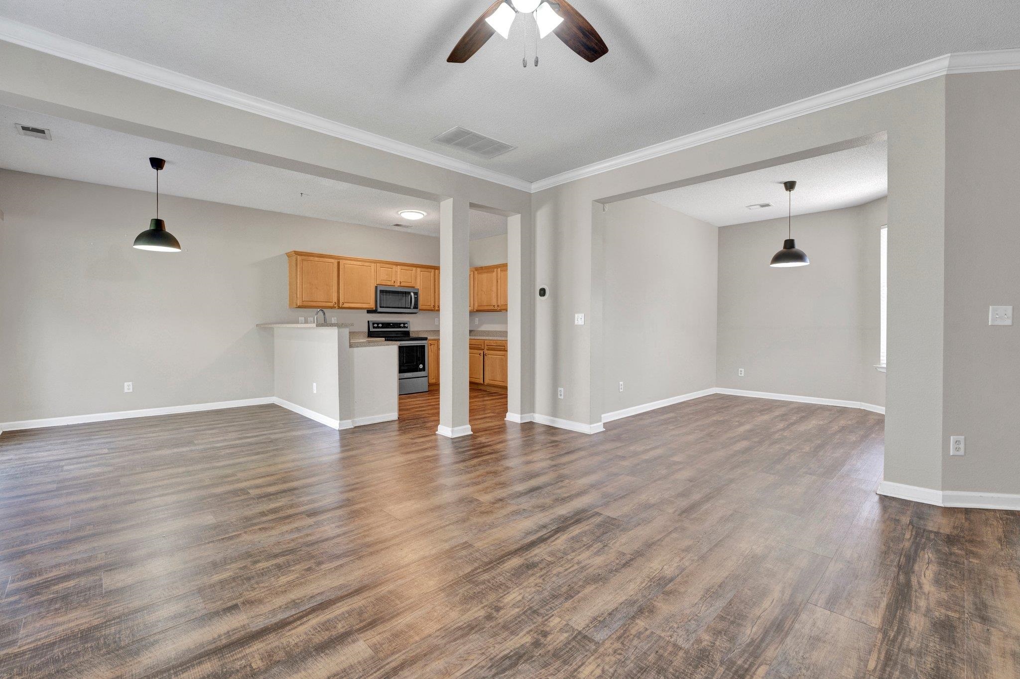 Unfurnished living room featuring ornamental molding, dark hardwood / wood-style floors, and ceiling fan