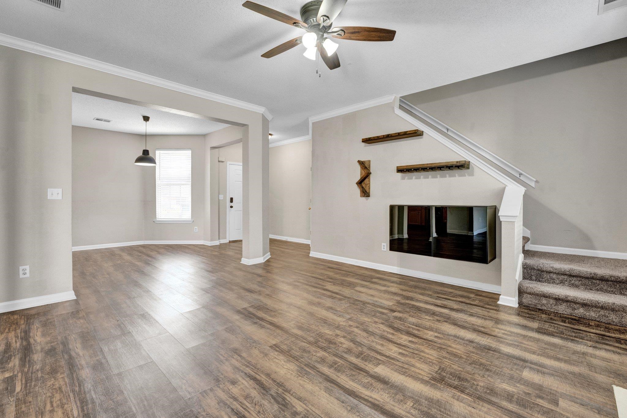 Unfurnished living room featuring ceiling fan, crown molding, and dark hardwood / wood-style flooring