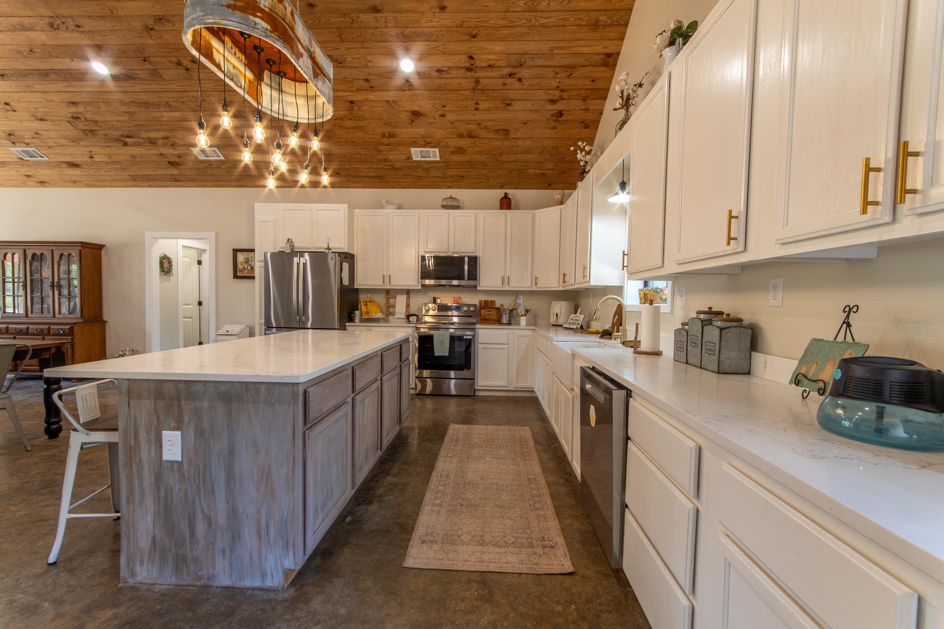 Kitchen with white cabinets, a kitchen island, appliances with stainless steel finishes, and wooden ceiling