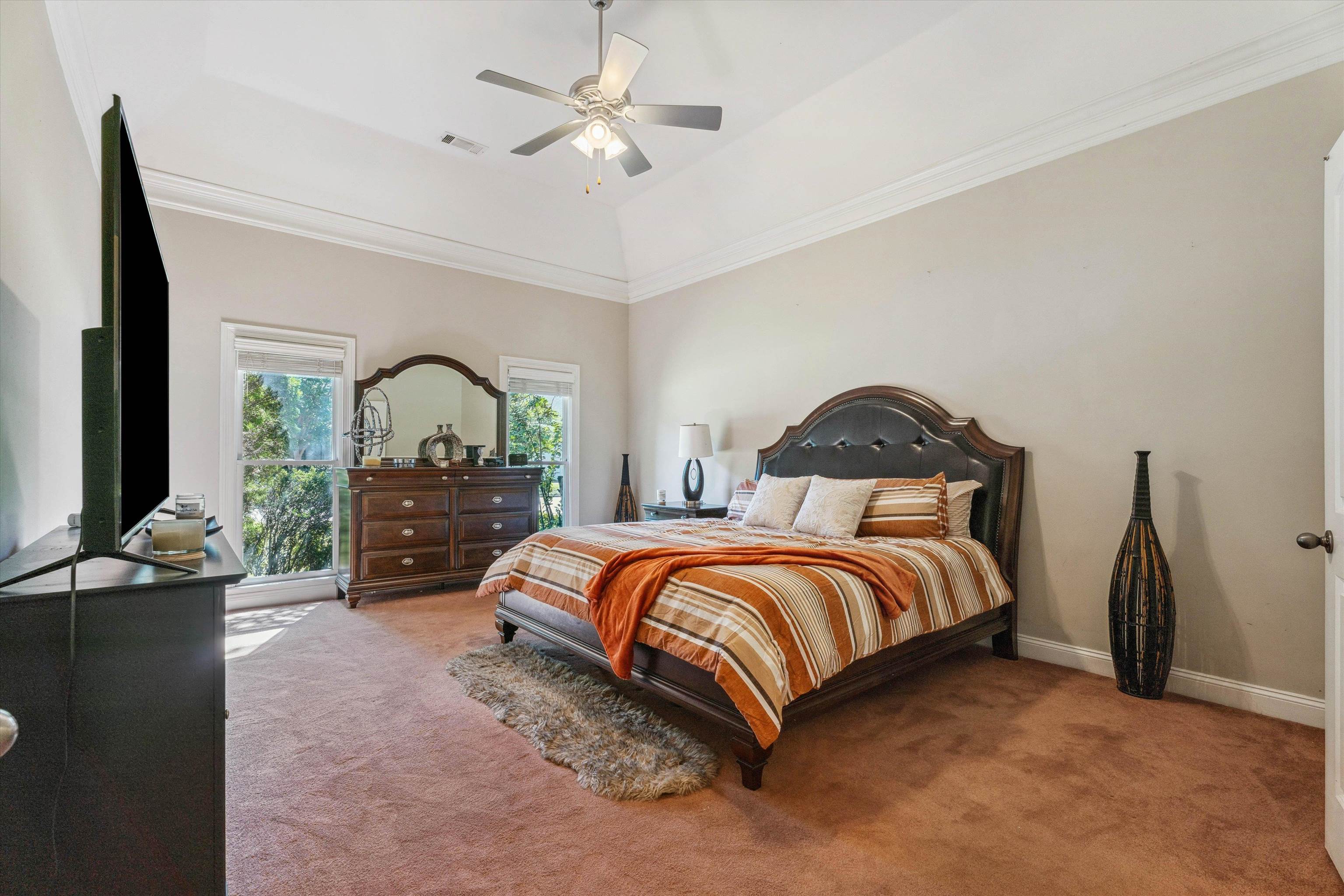 Carpeted bedroom with ceiling fan and ornamental molding