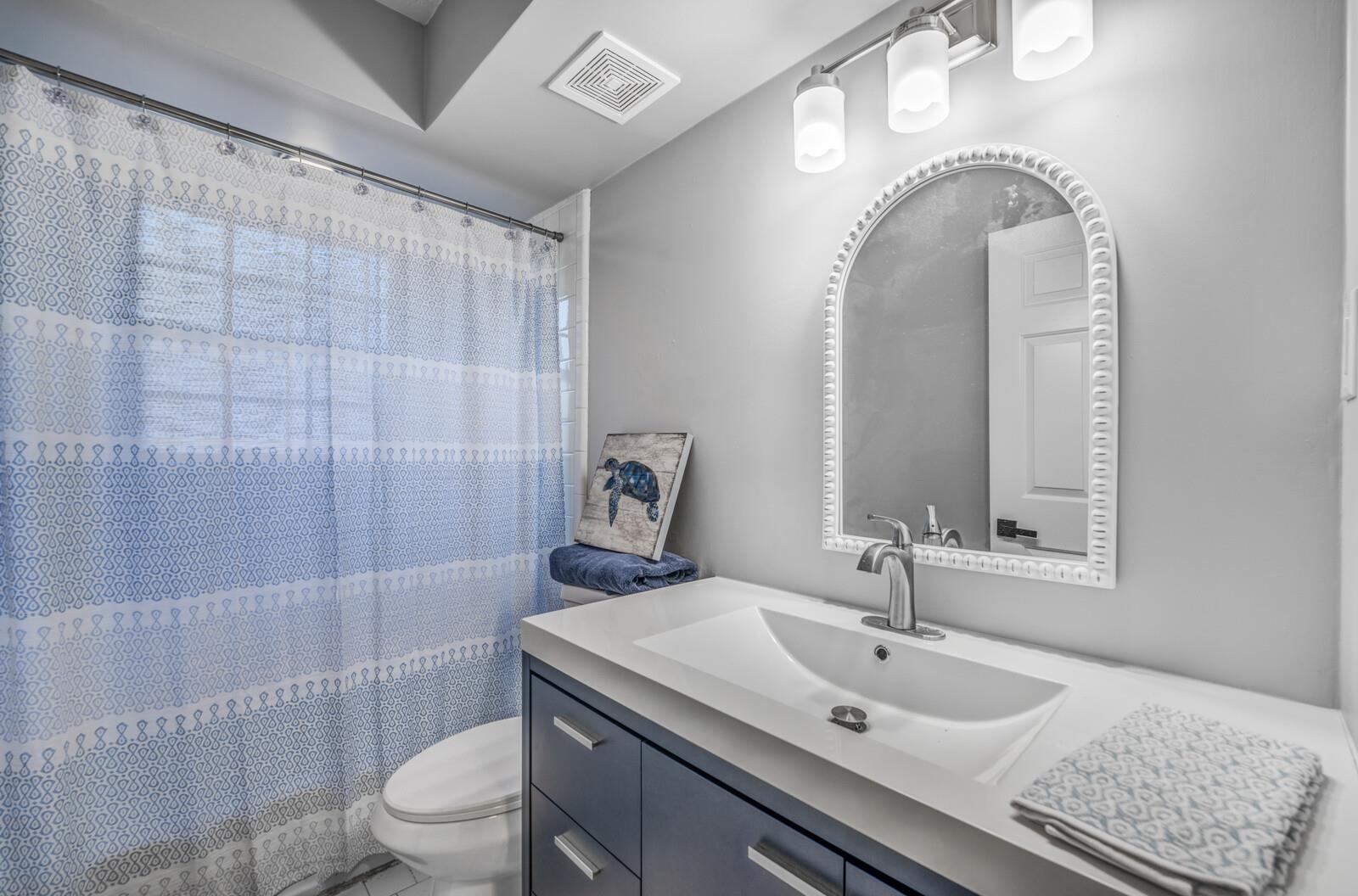 Bathroom featuring curtained shower, vanity, and toilet