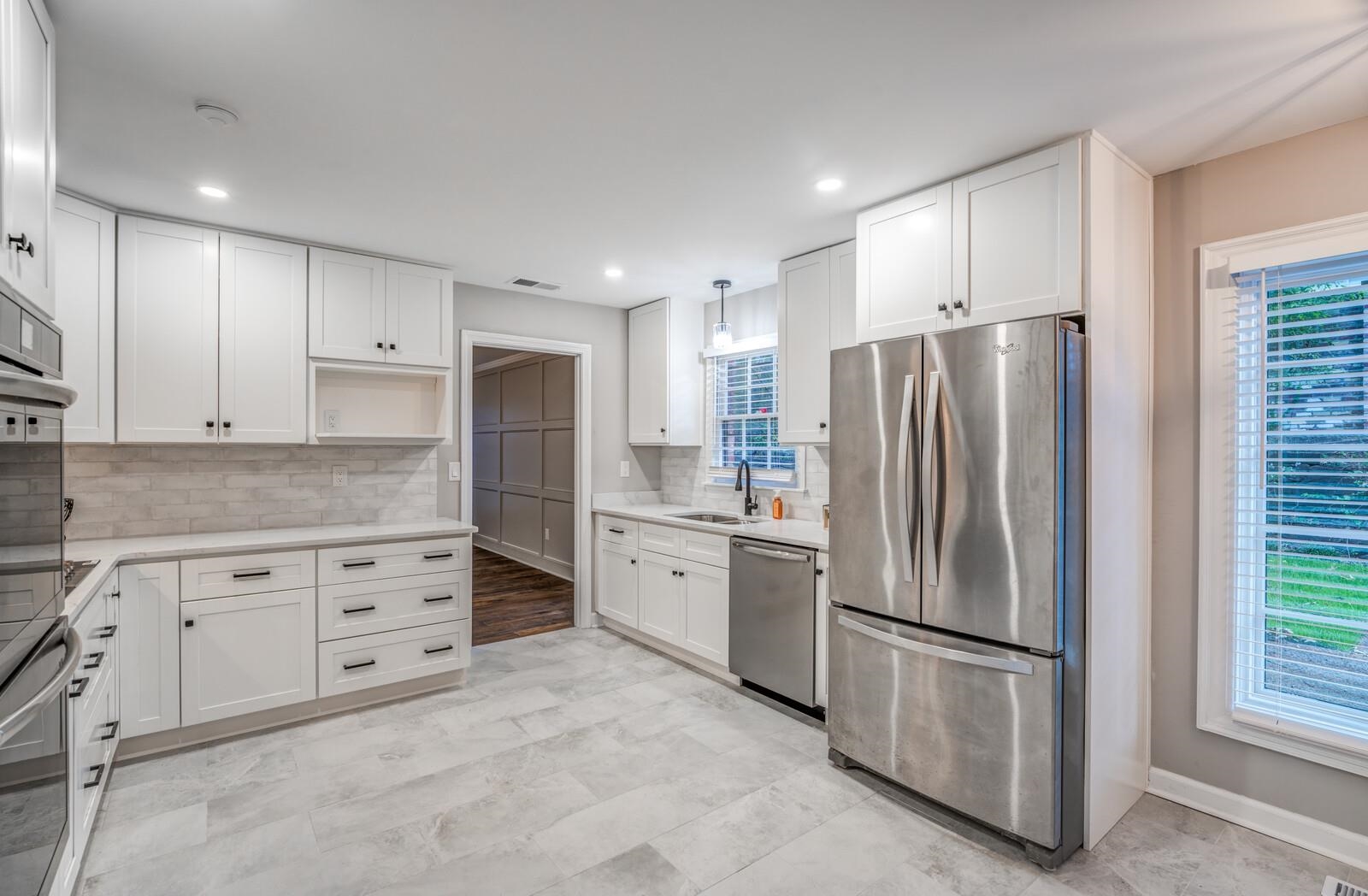 Kitchen featuring white cabinets, appliances with stainless steel finishes, and a wealth of natural light