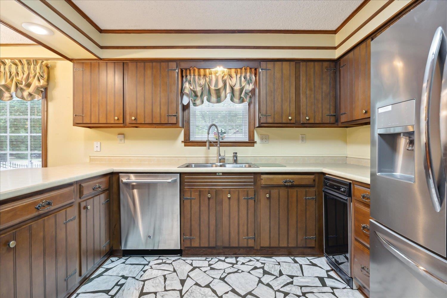 Kitchen with a textured ceiling, stainless steel appliances, crown molding, and sink