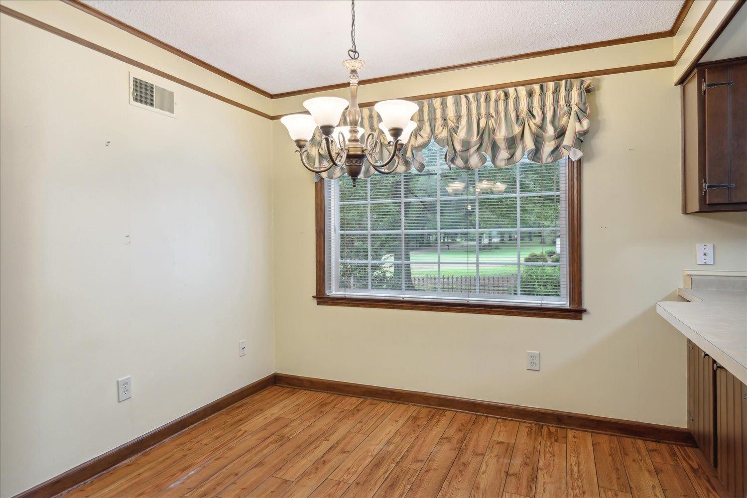 Unfurnished dining area with ornamental molding, a chandelier, light hardwood / wood-style floors, and a textured ceiling