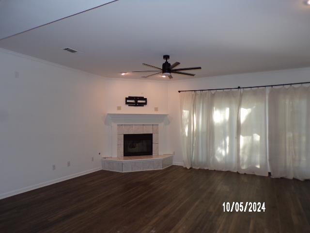 Unfurnished living room featuring a fireplace, ceiling fan, and dark wood-type flooring