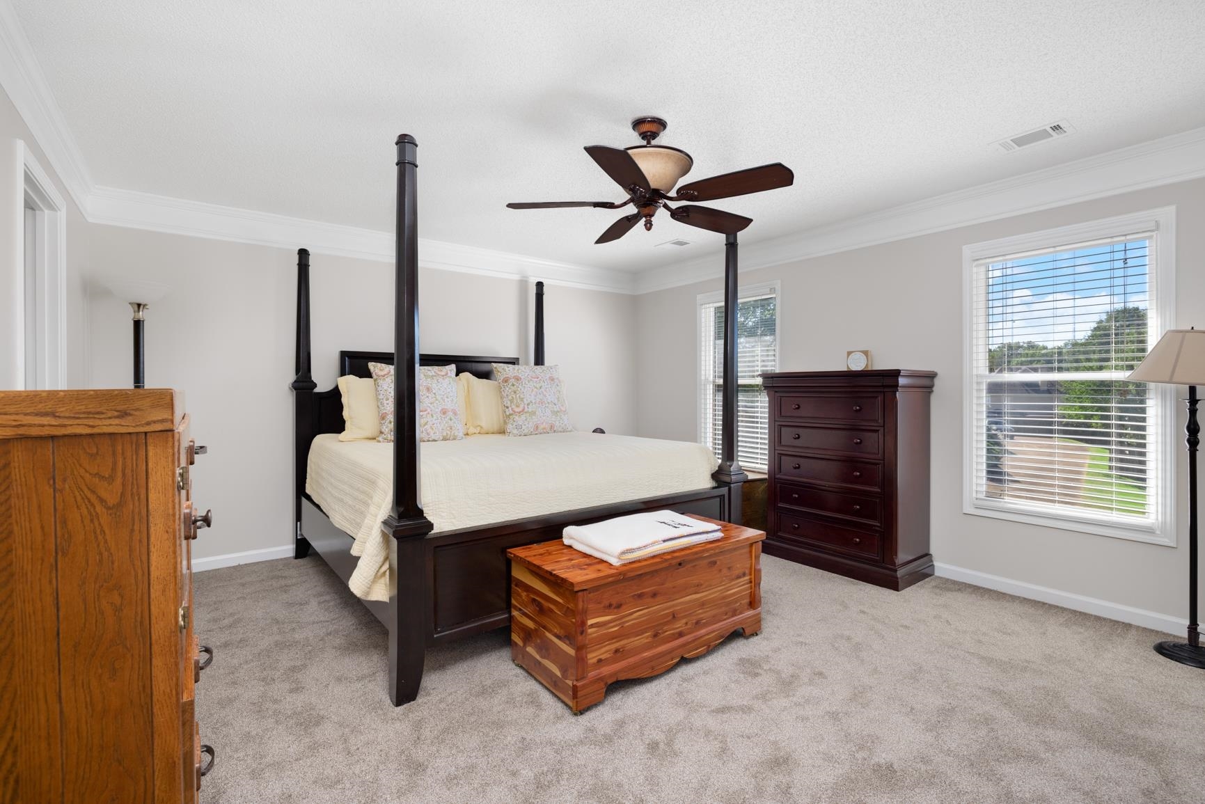 Newly carpeted bedroom with ornamental molding and ceiling fan