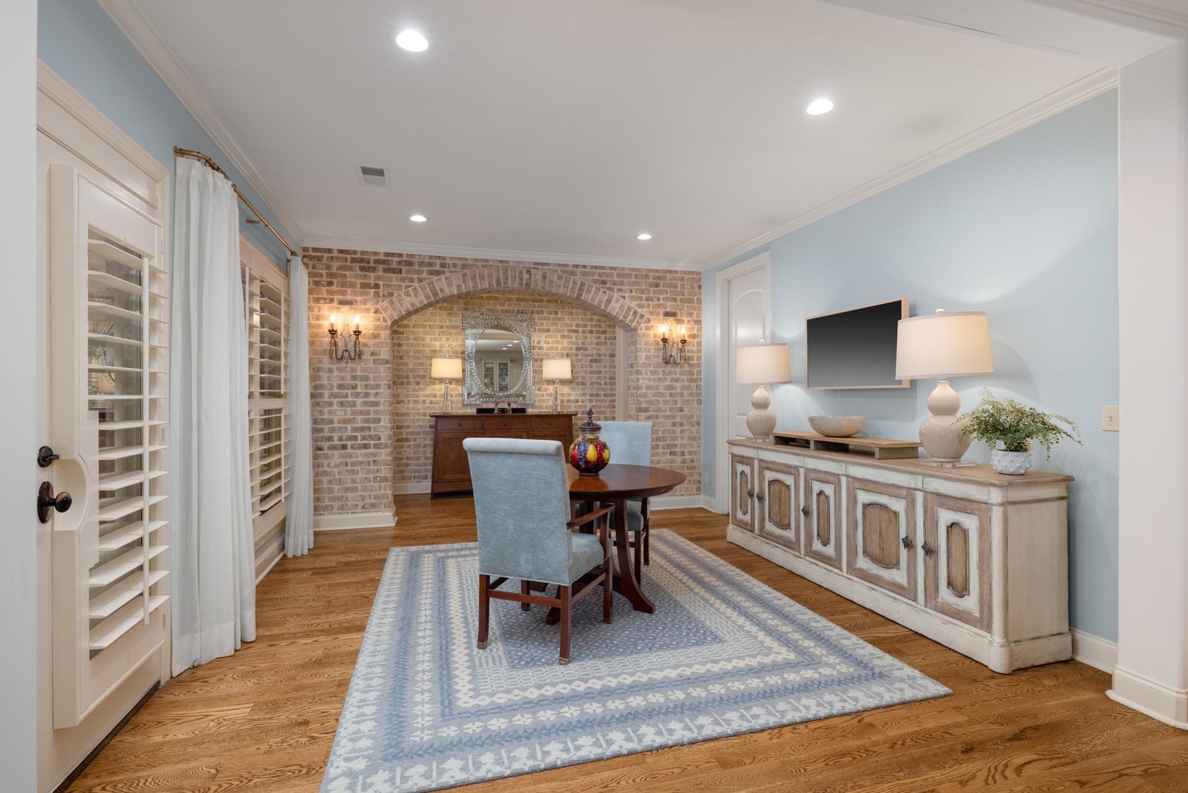 Dining room featuring brick wall, light hardwood / wood-style flooring, and crown molding