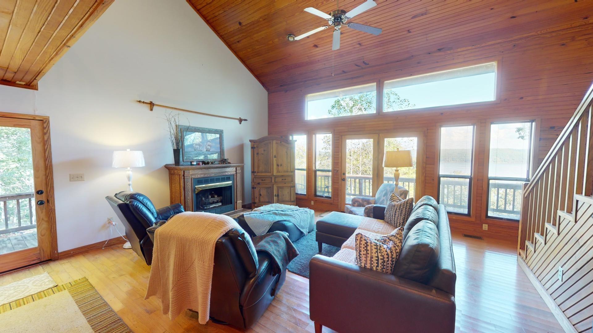 Living room with a healthy amount of sunlight, light hardwood / wood-style floors, and high vaulted ceiling