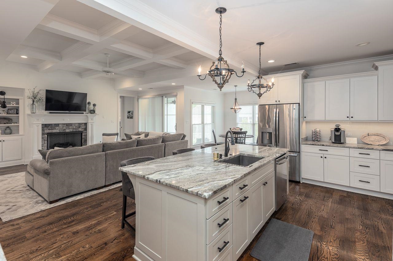 Kitchen featuring a kitchen island with sink, sink, stainless steel appliances, and white cabinetry