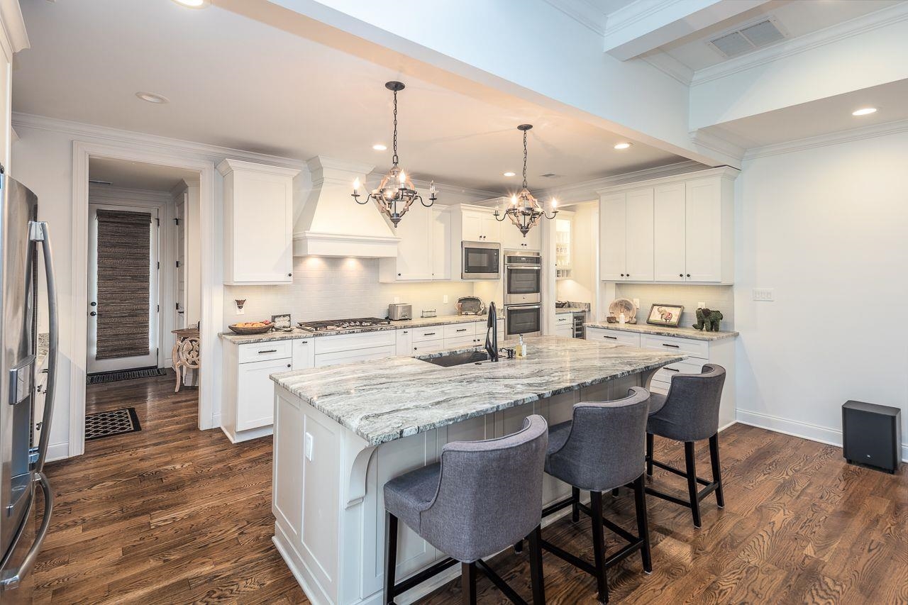 Kitchen with appliances with stainless steel finishes, a center island with sink, sink, and white cabinets